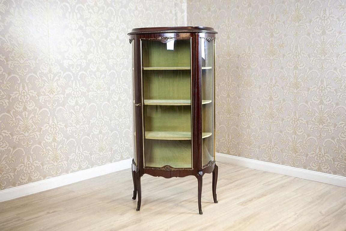 Display Cabinet from the Early 20th Century Veneered with Rosewood

We present you an elegant piece of furniture of a semi-round shape, decorated with brass ornamentations and moldings with a floral motif. The inside is lined with a fabric and
