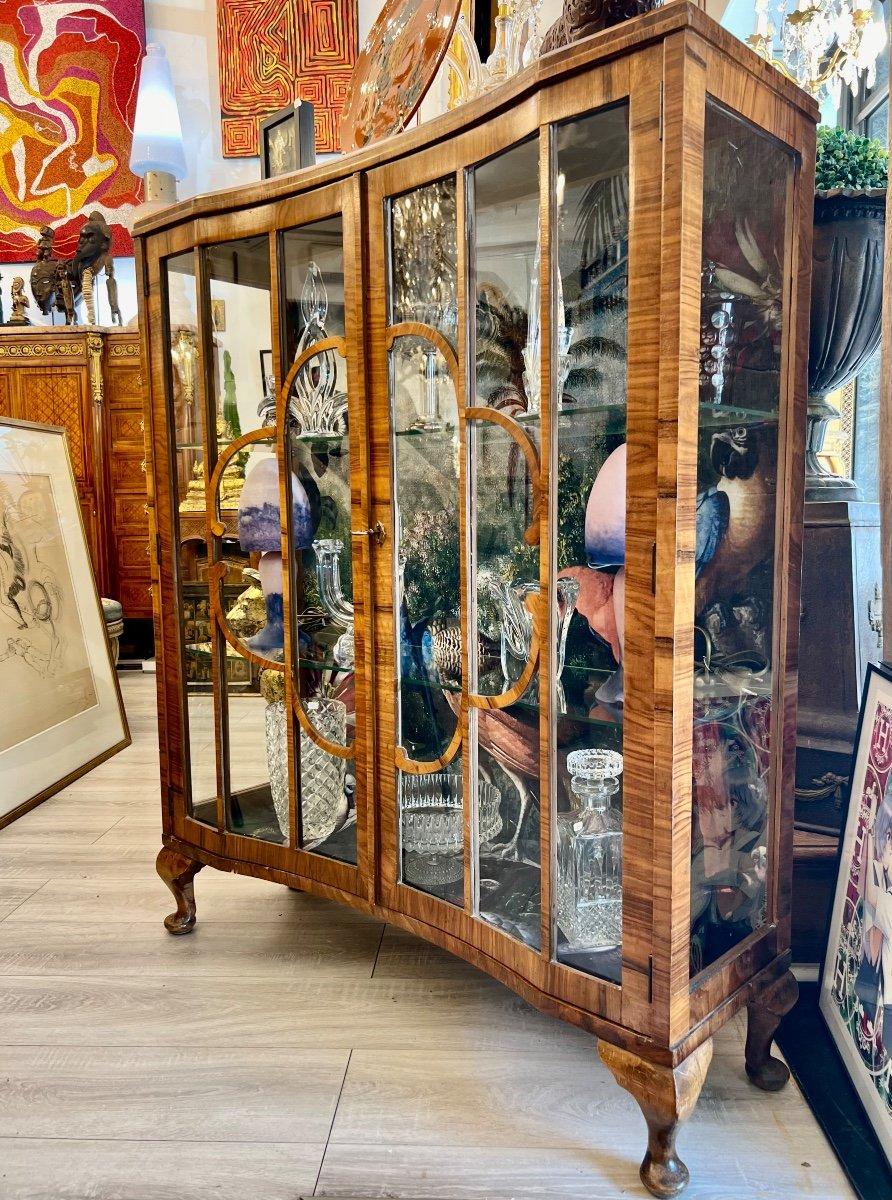 This unique display cabinet is a one-off piece from early 20th century France. It follows the style of Art Deco which flourished in the United States and Europe during the 1920s to early 1930s. It features two curved doors opening to three glass