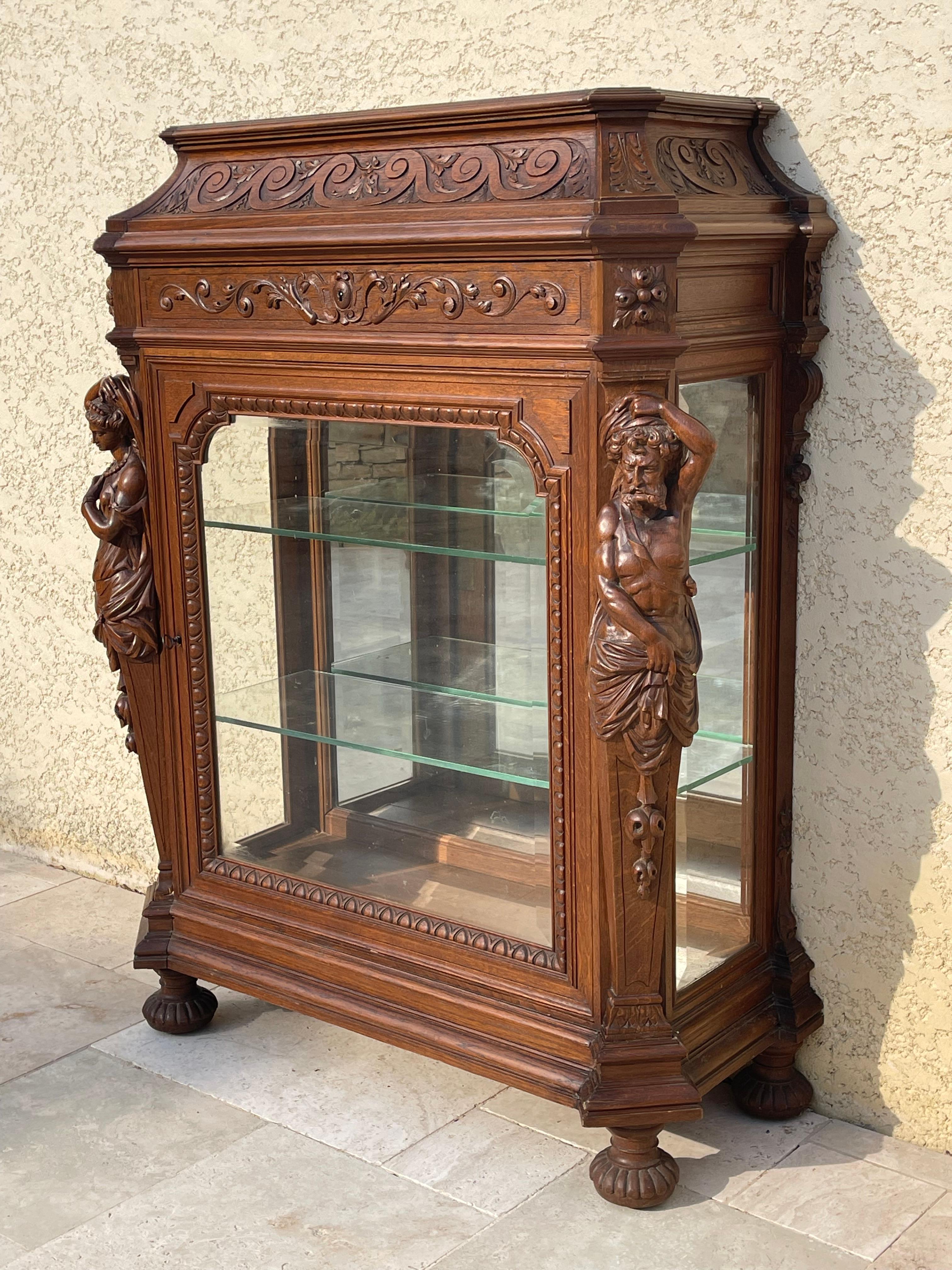 Magnificent display cabinet, carved solid oak silver cabinet in Renaissance style from the second half of the 19th century French with a glass door and a drawer from Maison Fourdinois. Two figures, a woman and a bearded man adorn the front. The