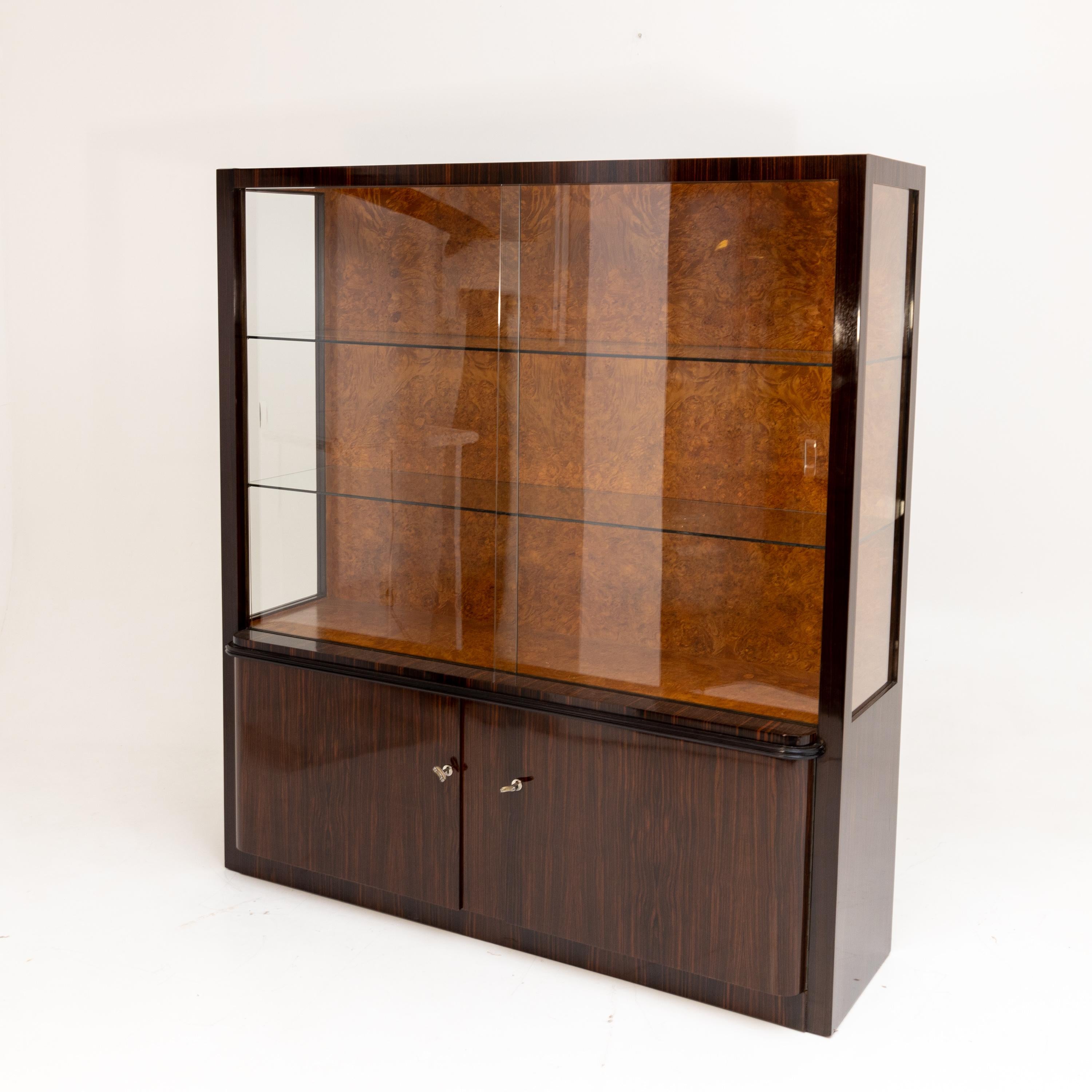 Large display case in the style of Bruno Paul, Deutsche Werkstätten Hellerau, Dresden. The two-door base is closed by a narrow profiled strip above which rises the large display case top. This is glazed on three sides and has two glass shelves and