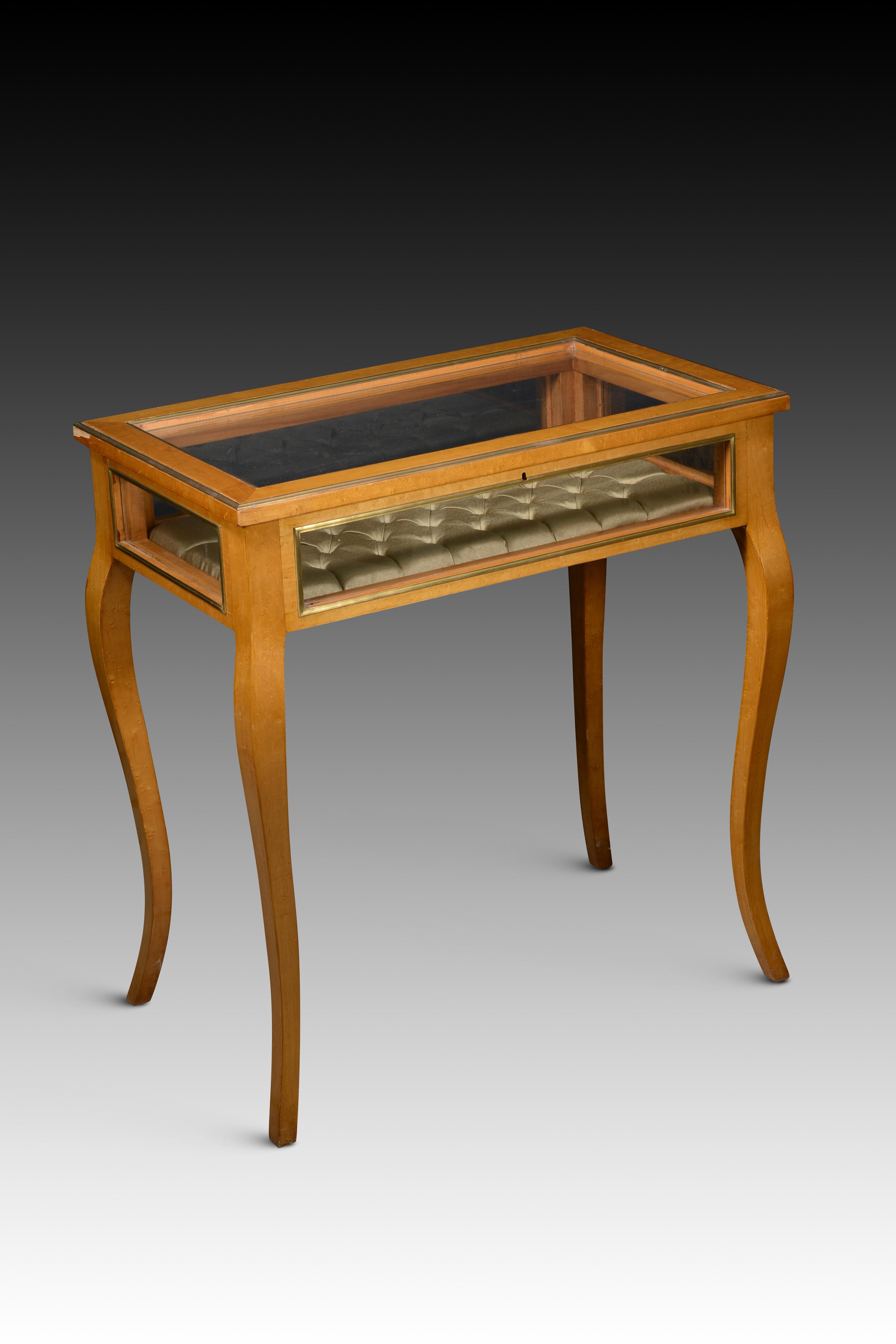  Display table in lemon-coloured wood. 
The rectangular display case rests on four cabriolet legs, with glass on all five sides (sides, front and top) framed by fine mouldings in gold metal and a front lock with a key. The interior is upholstered in