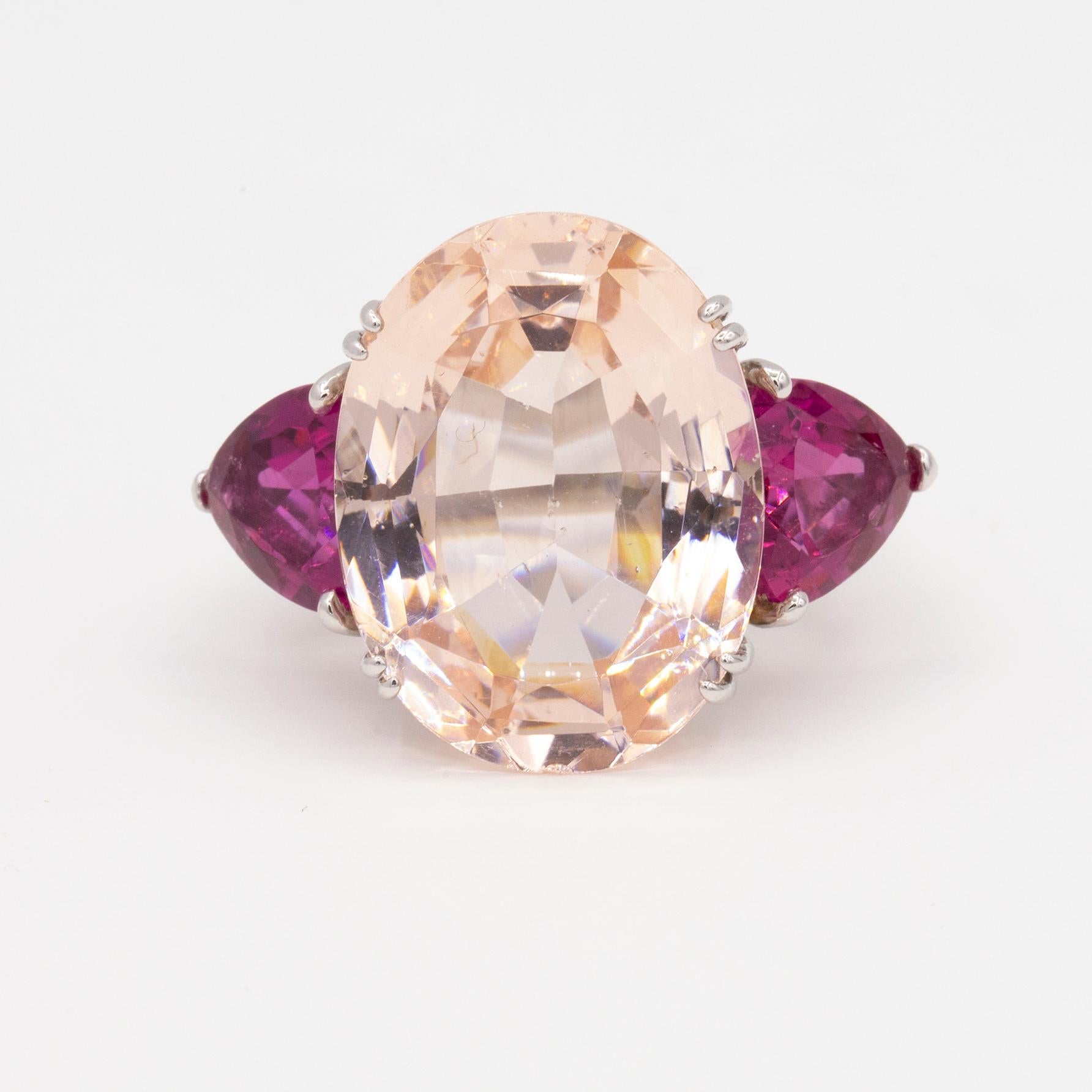 For a truly unique interpretation of the classic 3-stone ring.  A stunning handmade ring in platinum with an oval morganite set in the center and flanked by two trillion shaped pink tourmalines. 

The morganite weighs 25.32 carats and the