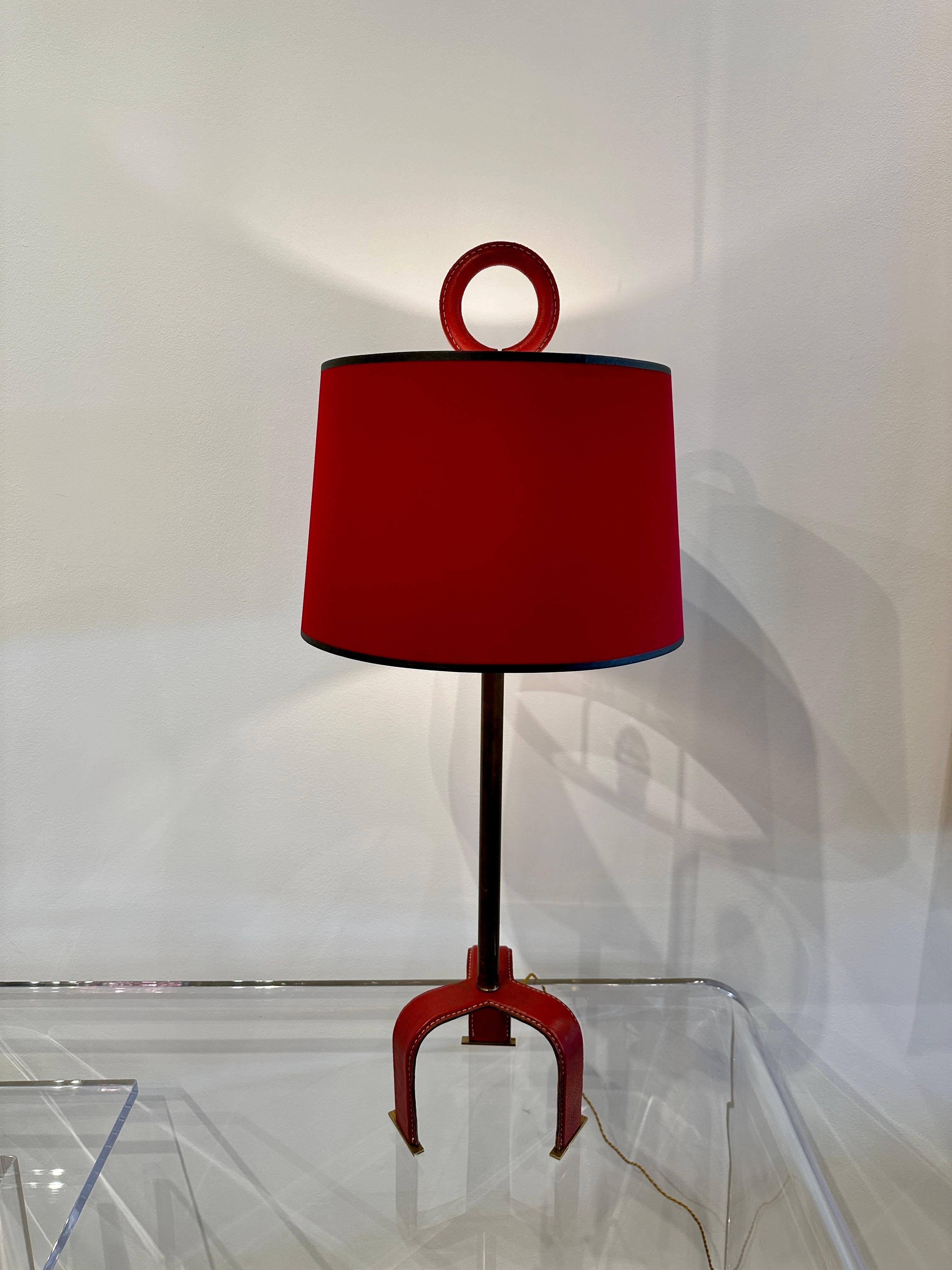 Completely authentic red stitched leather lamp by Jacques Adnet style with rare loop leather finial and tri-pod leg. Vintage custom red paper shade shown is included. Fully updated electrical socket, harp, switch plug and silk wiring. Original