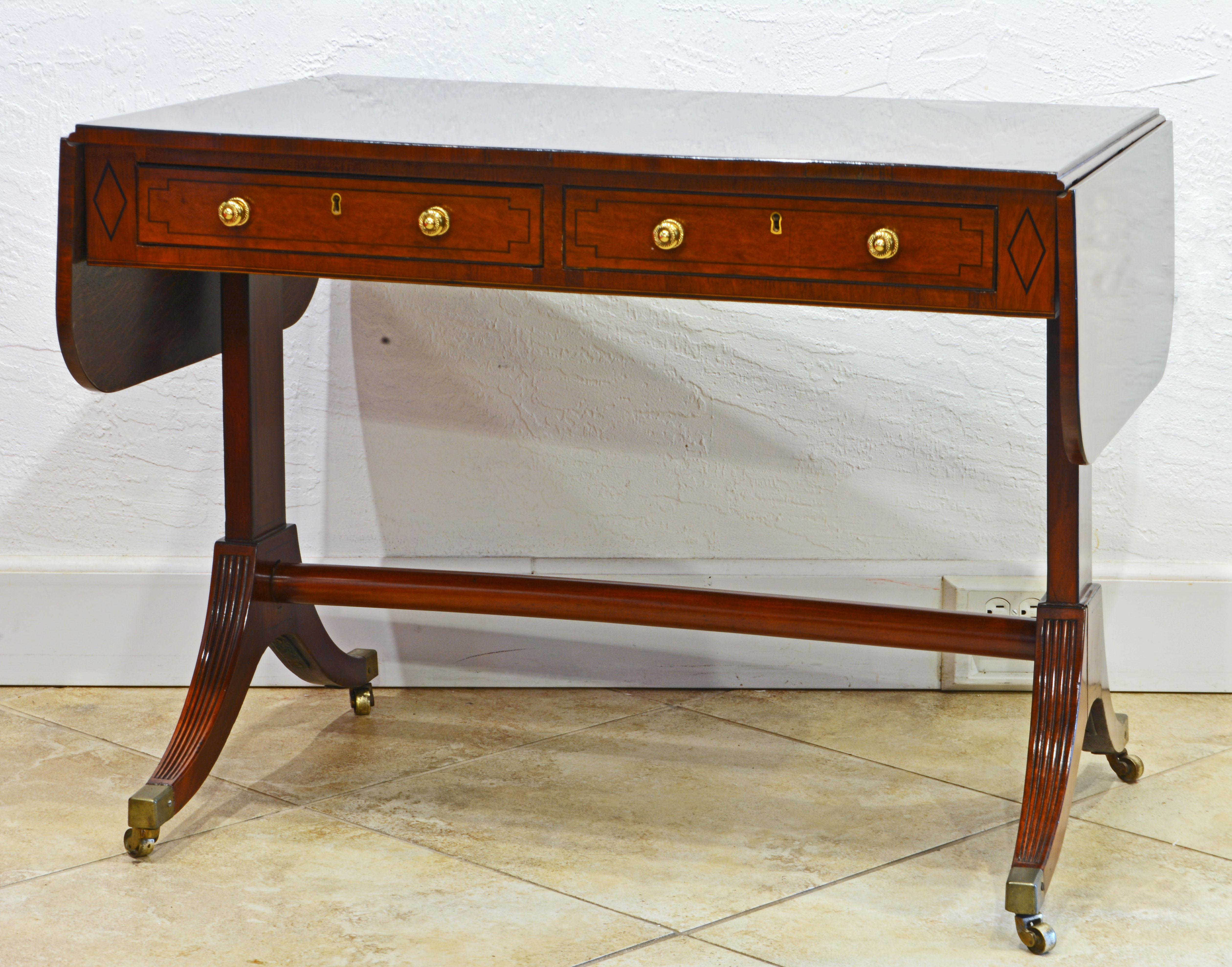 This distinguished English George III mahogany sofa table dating to around 1830 features a polished top and two drop leaves that can be lifted and supported to make the table longer. Under the top there are two drawers on one side and two simulated