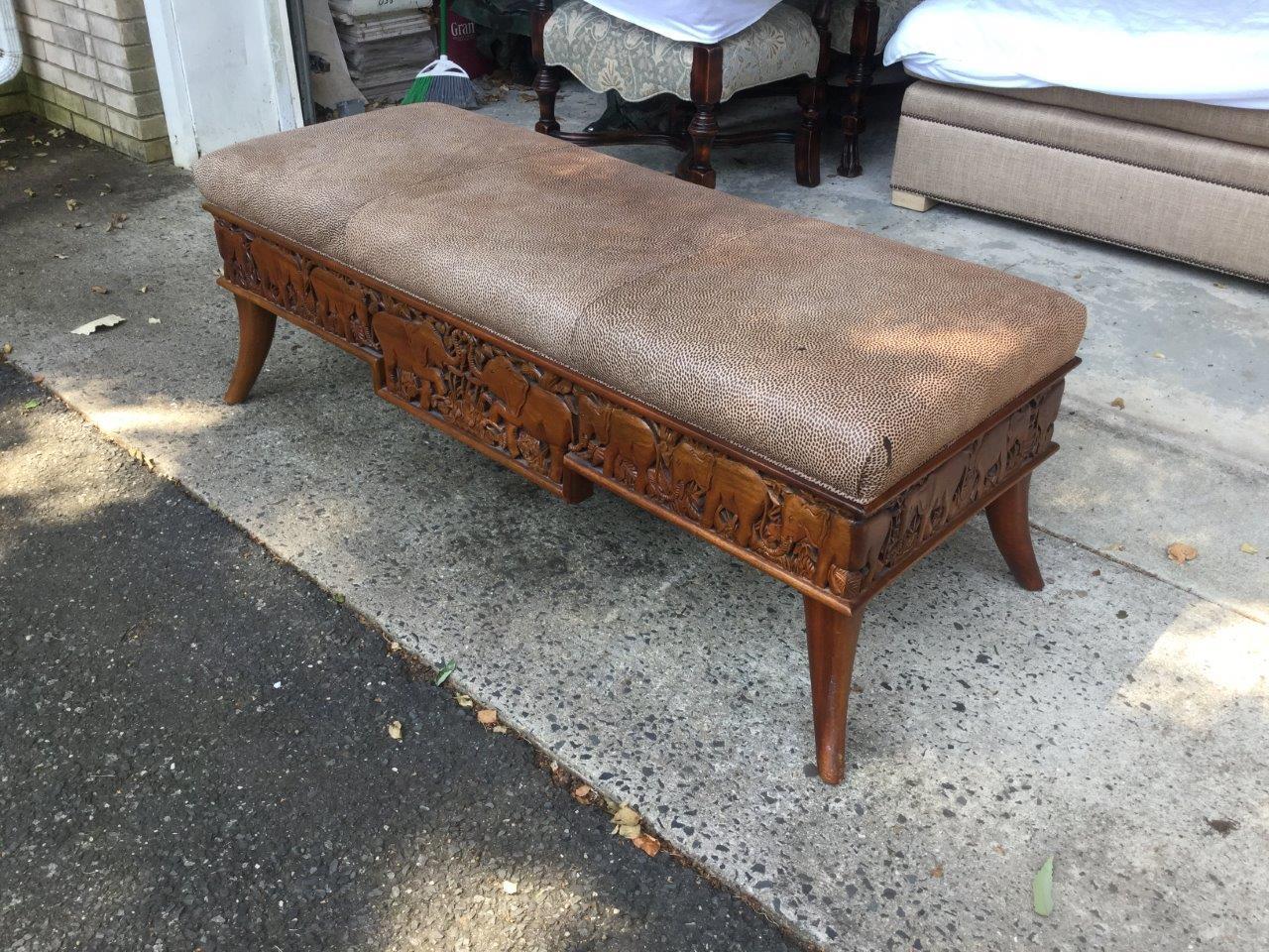 Handsome African tribal theme carved wood rectangular bench featuring elephants on all four sides. Long and wide, this bench can be used for extra seating, or as a coffee table in front of a sofa. The upholstery is printed leather which imitates an