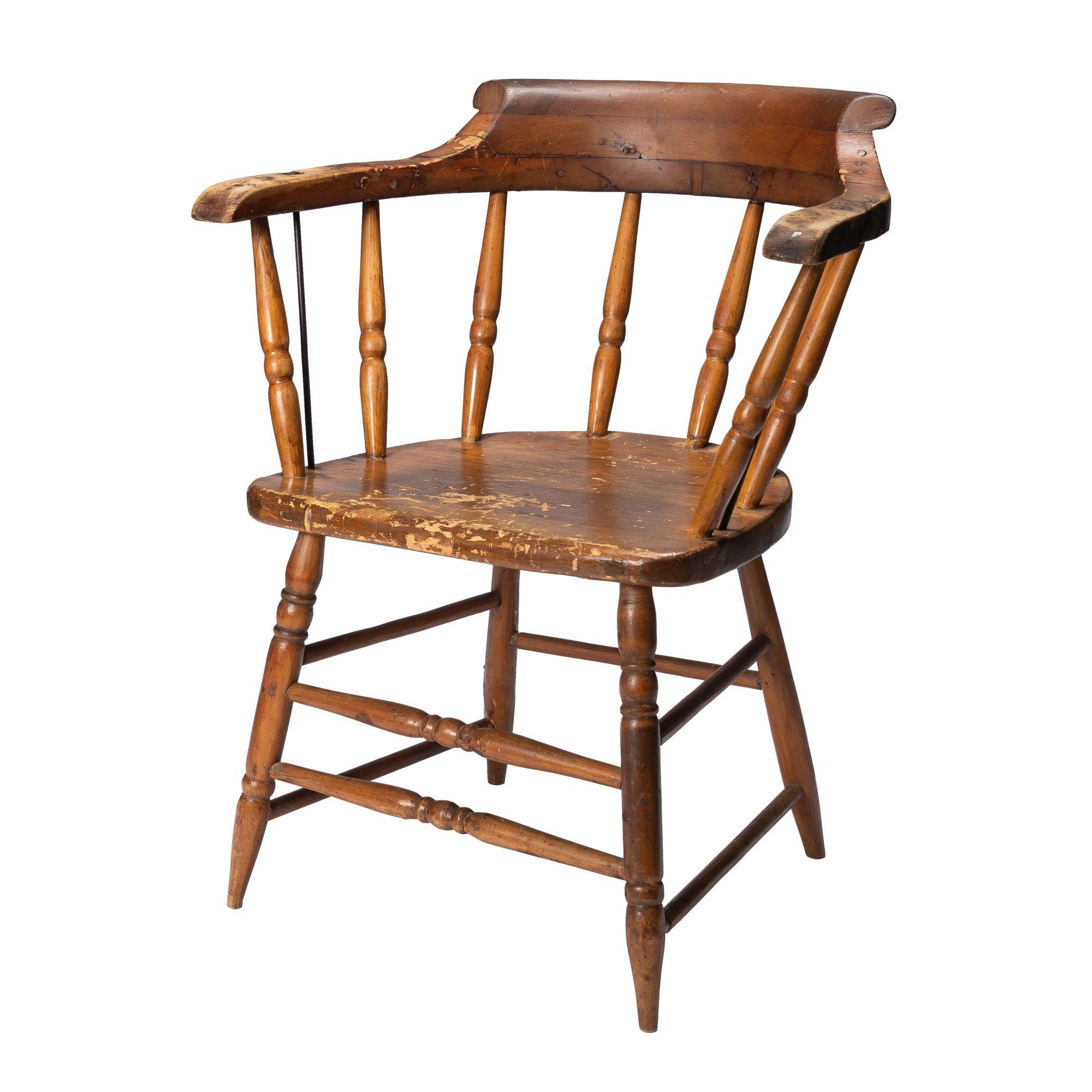 American Windsor firehouse chair with a continuous arm yolk back. The crest rail has an applied scroll raised above the arms, and the entire yoke is supported by eight turned spindles morticed into the plank seat. The turned legs are doweled into