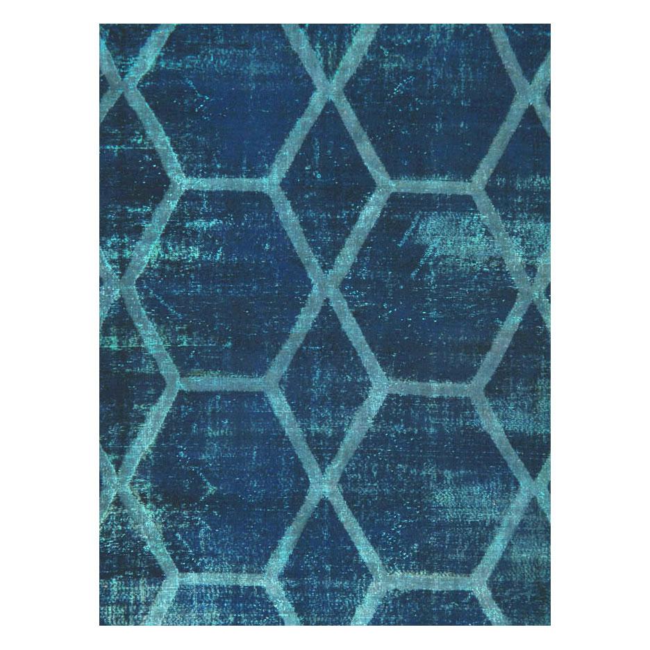 Cette création du XXIe siècle consiste en un tapis persan Tabriz vintage, fabriqué à la main au milieu du XXe siècle, qui a été gratté et surteint en bleu pour lui donner un aspect vieilli. Bien que l'aspect soit usé, le tapis est en très bon état