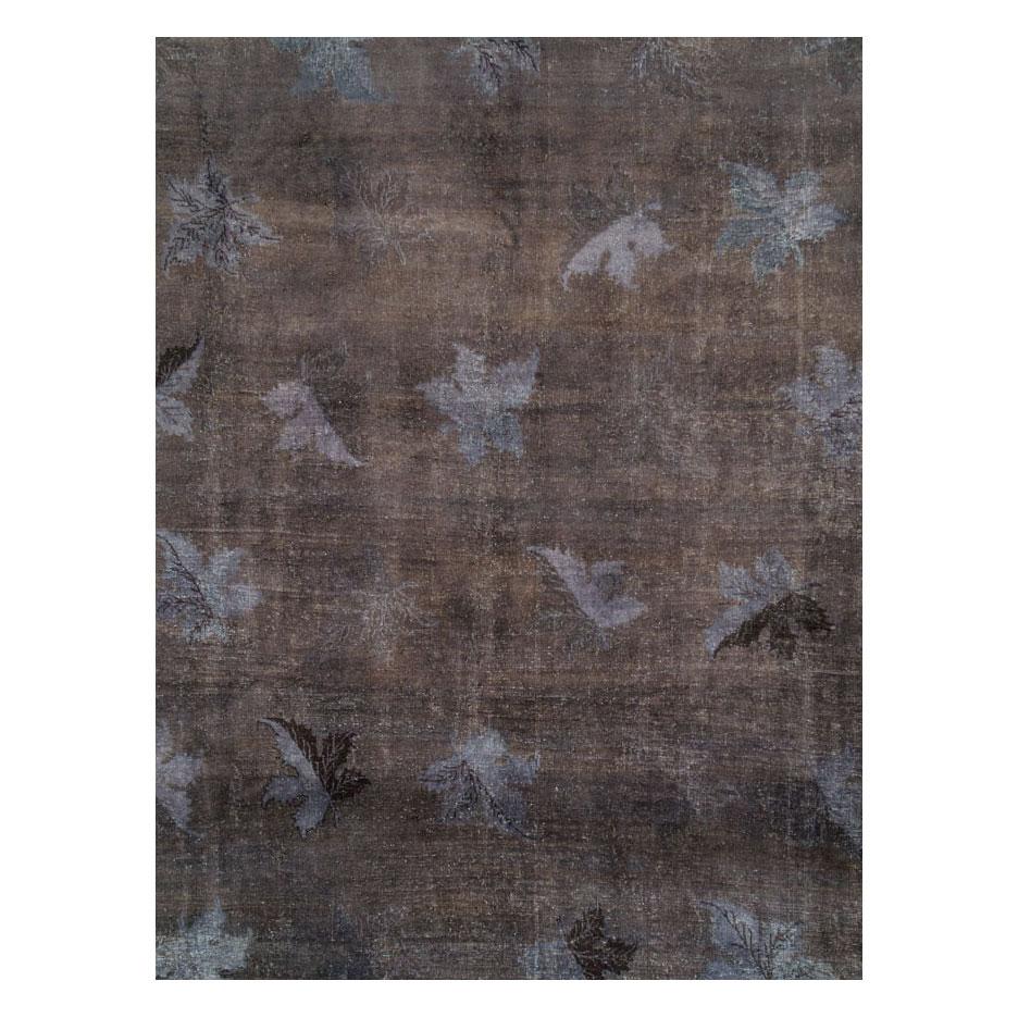 This 21st century creation consists of a vintage Persian Mashad rug handmade during the mid-20th century that was scraped and overdyed charcoal to produce a distressed appeal. Although the look is distressed, the rug is in very strong and durable