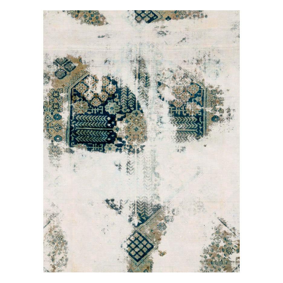 This 21st century creation consists of an antique Persian Tabriz rug handmade during the early 20th century that was scraped and overdyed to produce a distressed appeal. Although the look is distressed, the rug is in fact in very strong and durable