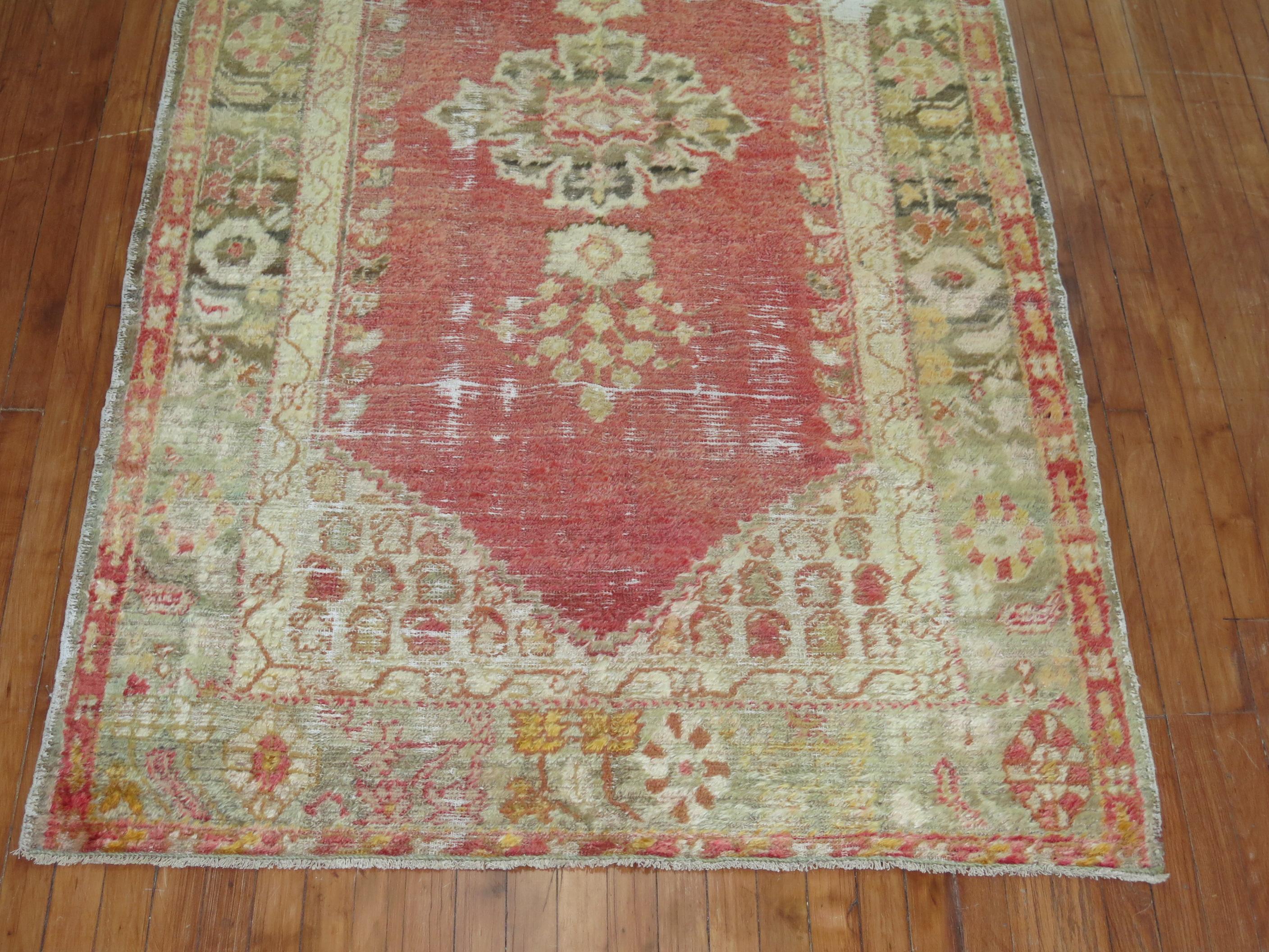An early 20th century angora wool Oushak rug with a soft watermelon colored ground on an open field and center medallion with the perfect amount of natural wear.
