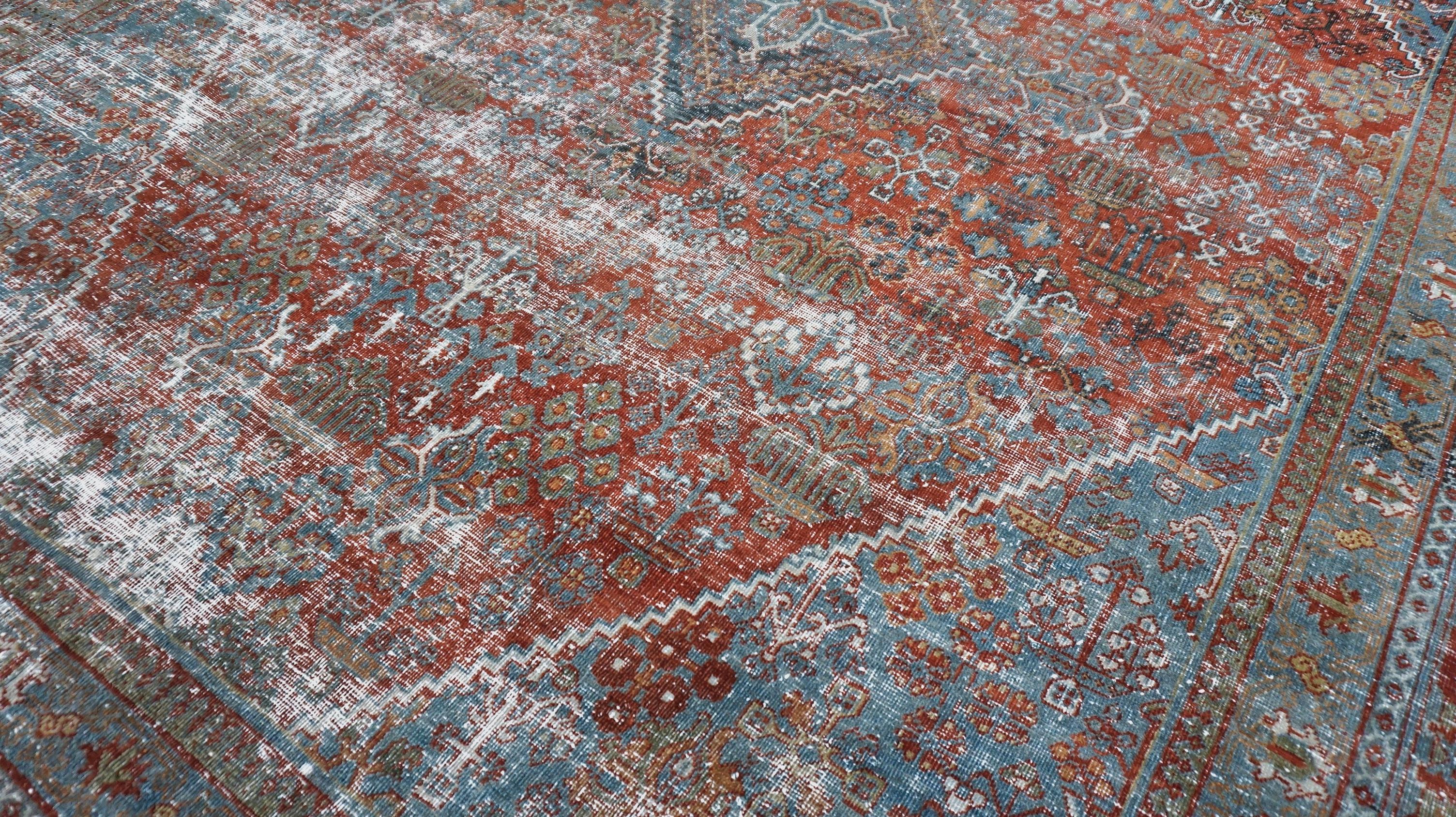 This striking Antique  Heriz hand-knotted wool rug features a bold geometric medallion design rendered in red and blue. The rug showcases the region's signature large-scale angular motifs and a strong central diamond medallion surrounded by