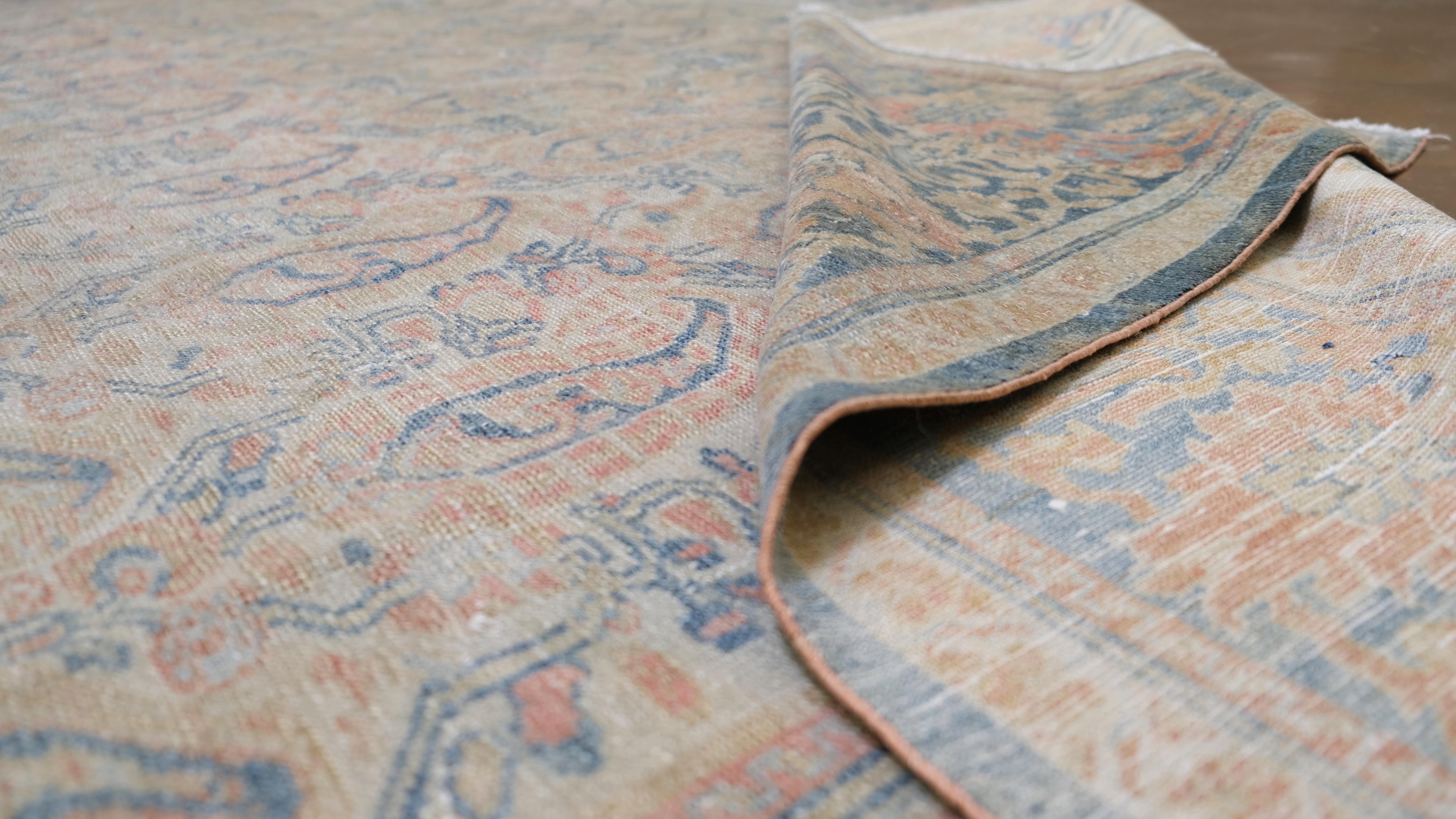 Questo squisito tappeto antico in lana annodato a mano è caratterizzato da un ipnotico motivo paisley boteh all-over, un motivo tradizionale che simboleggia l'abbondanza e la prosperità. I dettagliati disegni boteh, realizzati in morbido avorio, blu