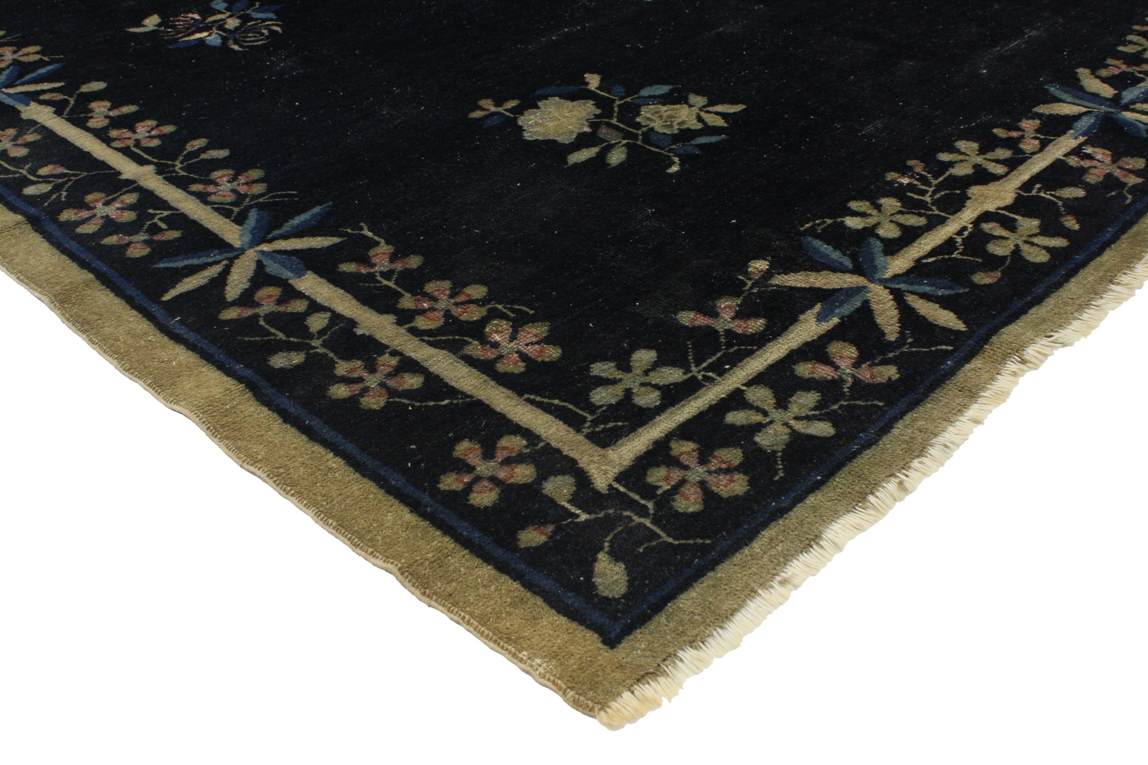 76682 distressed antique Chinese Peking rug with jazz age chinoiserie style. This hand knotted wool antique Chinese Peking rug features a variety of elegant floral motifs spread across an abrashed ink blue field. Large blooming lotuses float in the