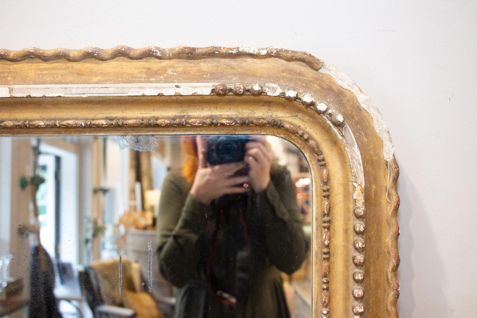 This antique French Louis Philippe mirror is truly stunning, as we believe the distressed and worn finish of its gilt plaster frame only increases its beauty. This mirror is a great size for installing on the wall of an entry, or above a large piece
