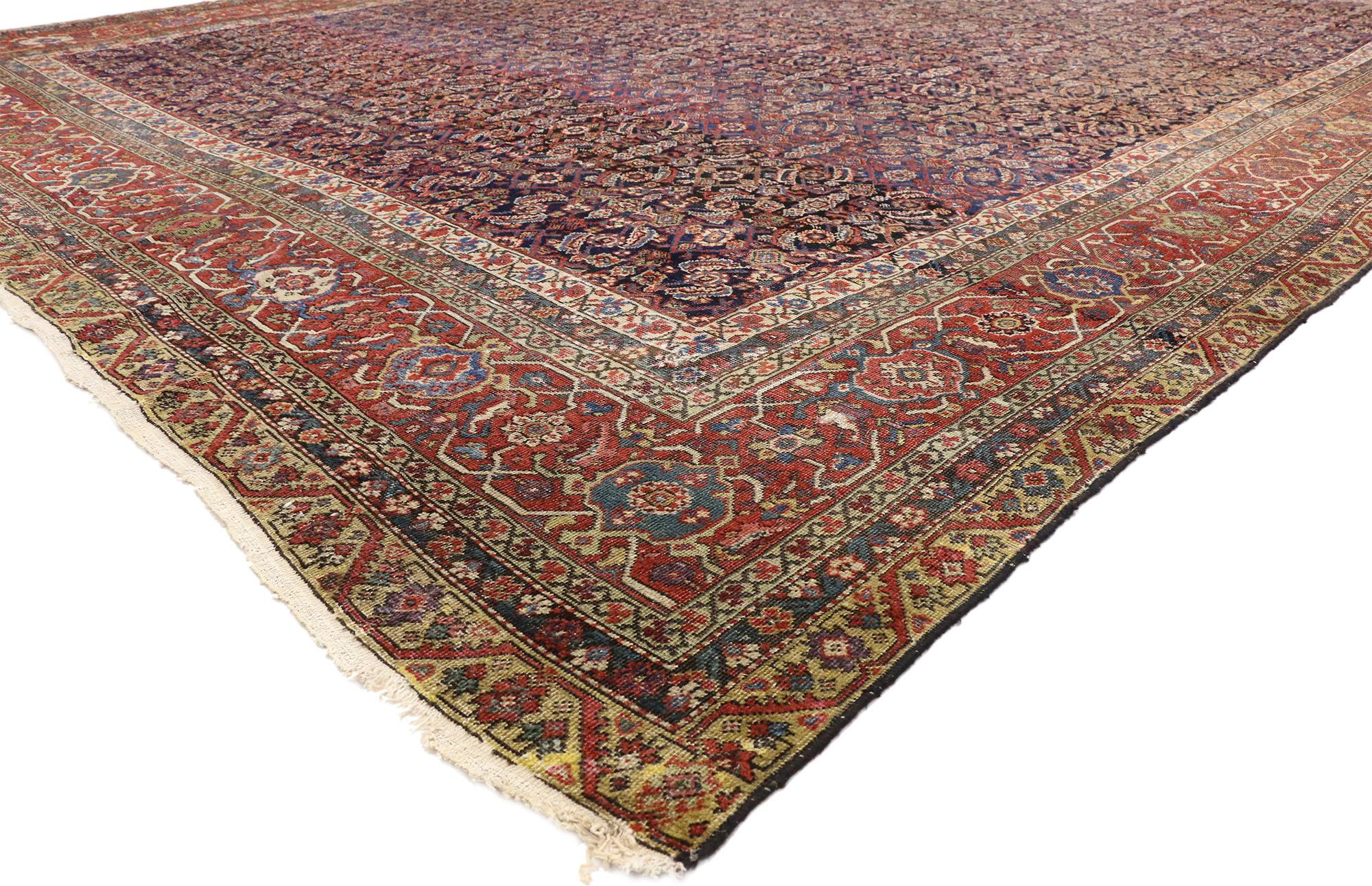 77207 Tapis Persan Farahan antique et vieilli, 12'03 x 16'04.
Ce tapis Farahan antique en laine nouée à la main présente un motif floral géométrique connu sous le nom de motif Herati sur un champ bleu encre et bleu marine abrasé. Le motif Herati est