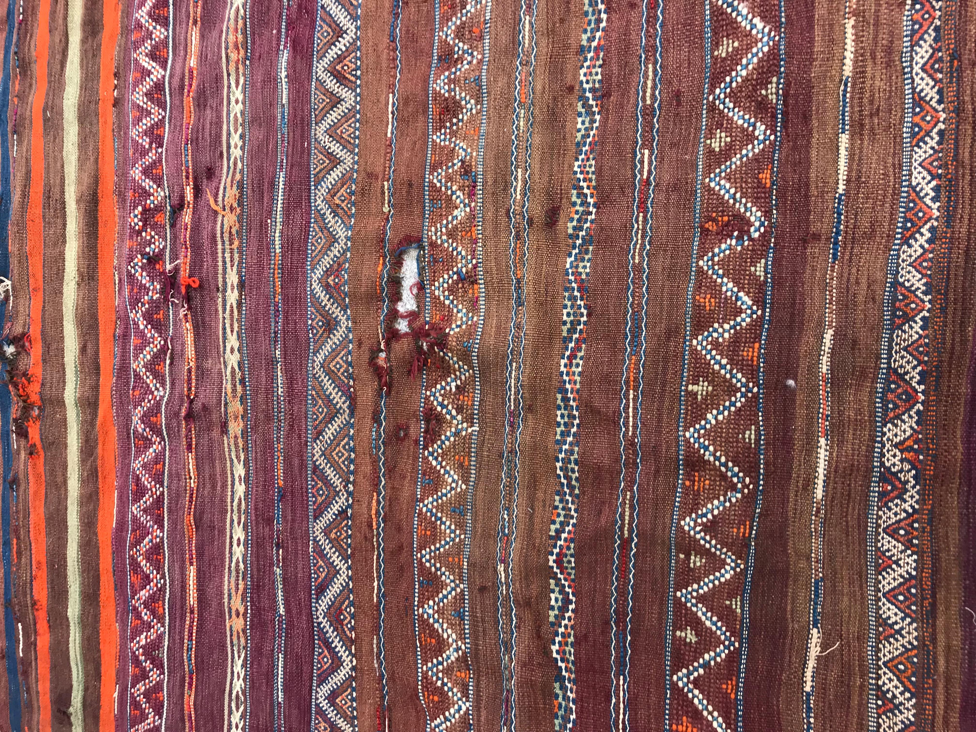 Kilim marocain tribal du début du 20e siècle avec un design tribal et géométrique et de belles couleurs avec du violet, de l'orange, du brun, du bleu et du vert, entièrement tissé à la main avec de la laine sur une base de laine.