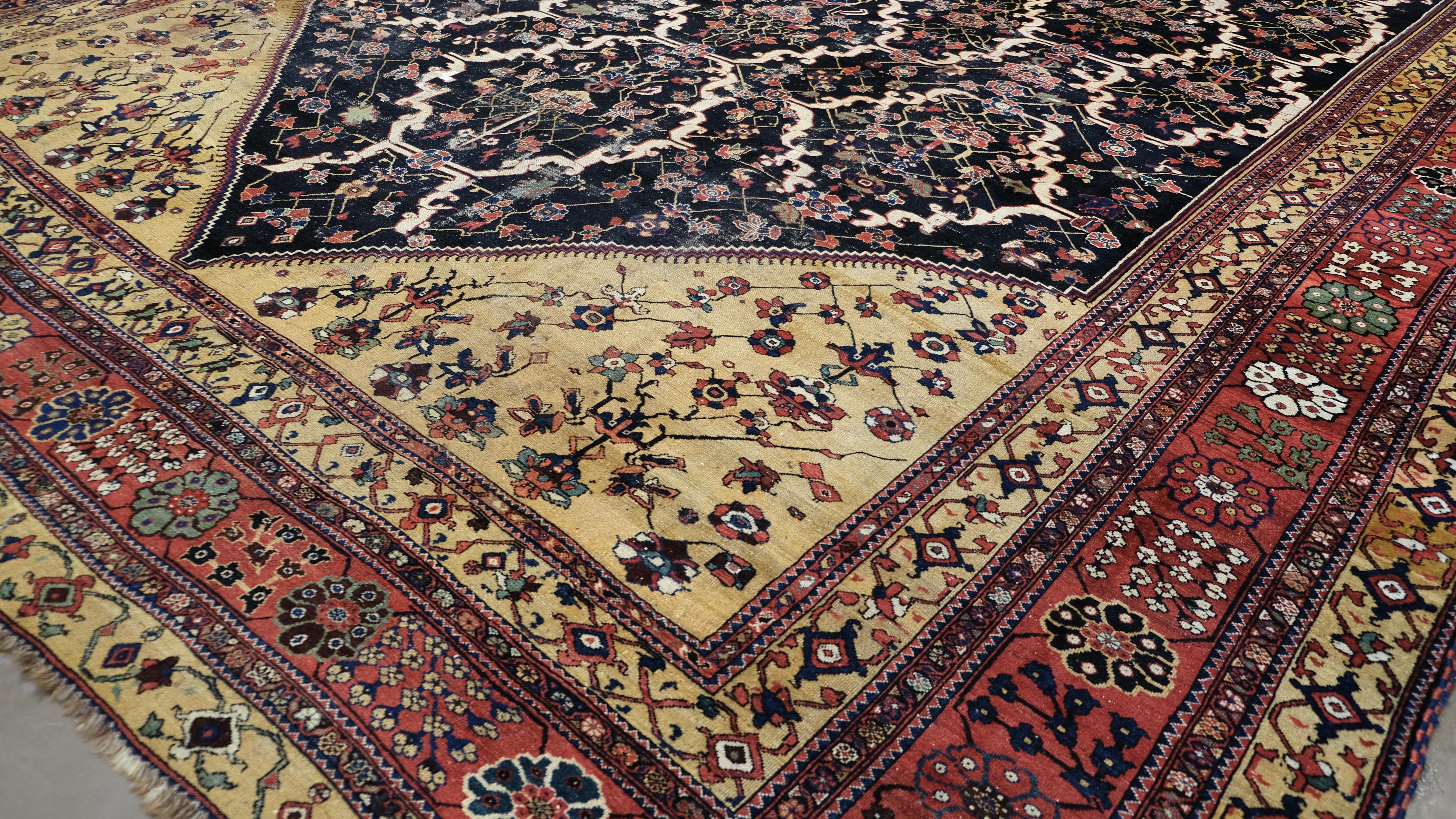 Dieser prächtige antike persische Farahan-Sarouk-Teppich, der um 1900 in der Region Arak im Iran gewebt wurde, ist ein bemerkenswertes Beispiel für raffinierte dörfliche Handwerkskunst und klassische persische Eleganz. Die weitläufige Komposition