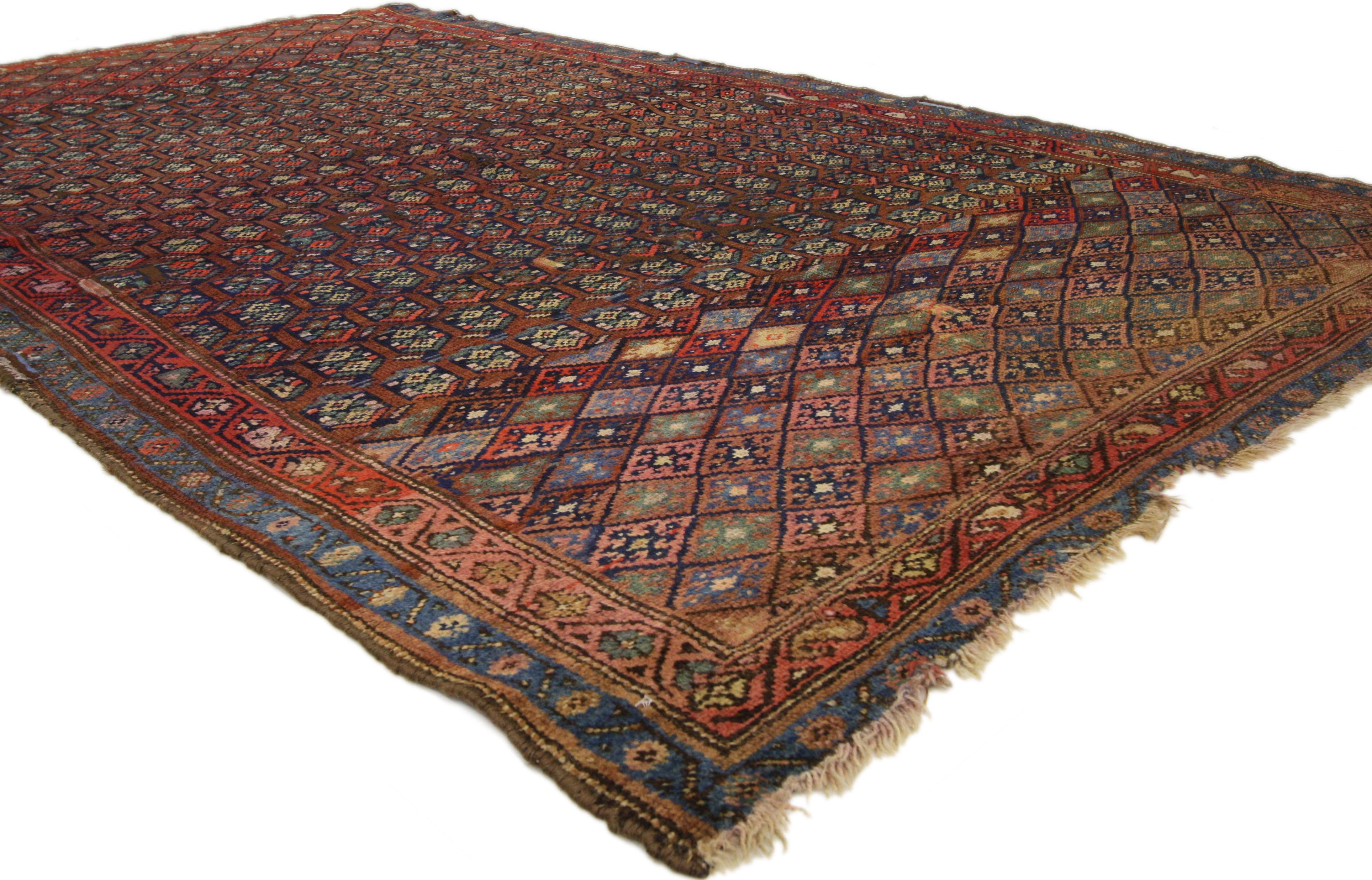 72611 distressed antique Persian Kurd rug with Adirondack Lodge style. This hand knotted wool distressed antique Persian Kurd rug features an all-over geometric pattern composed of lozenges and boteh motifs. It is enclosed with a double meander