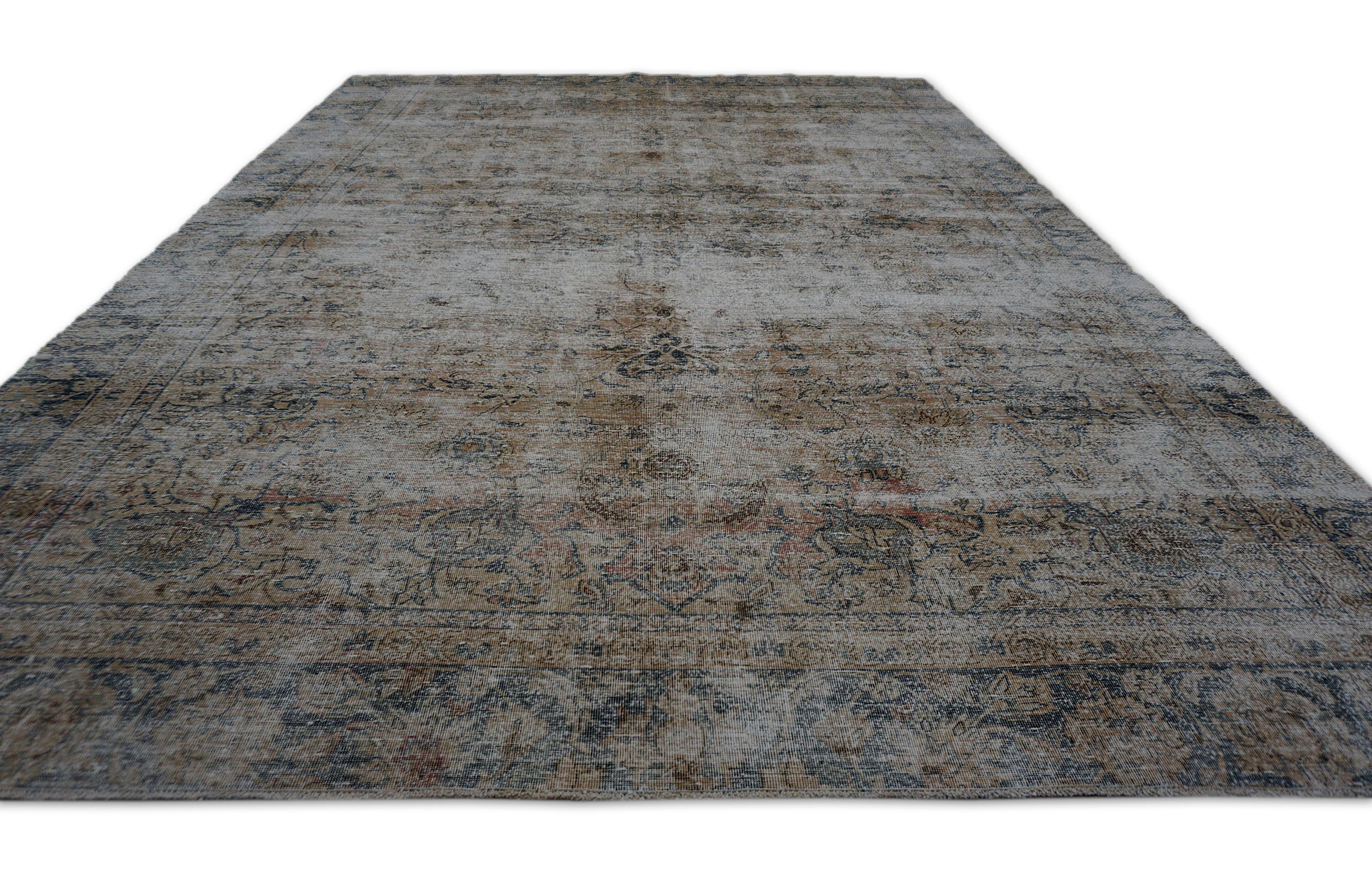 This exquisite hand-knotted wool rug showcases a beautifully distressed finish, reflecting the timeless artistry of Persian craftsmanship. The design features a central floral medallion surrounded by intricate vine and floral patterns, all carefully
