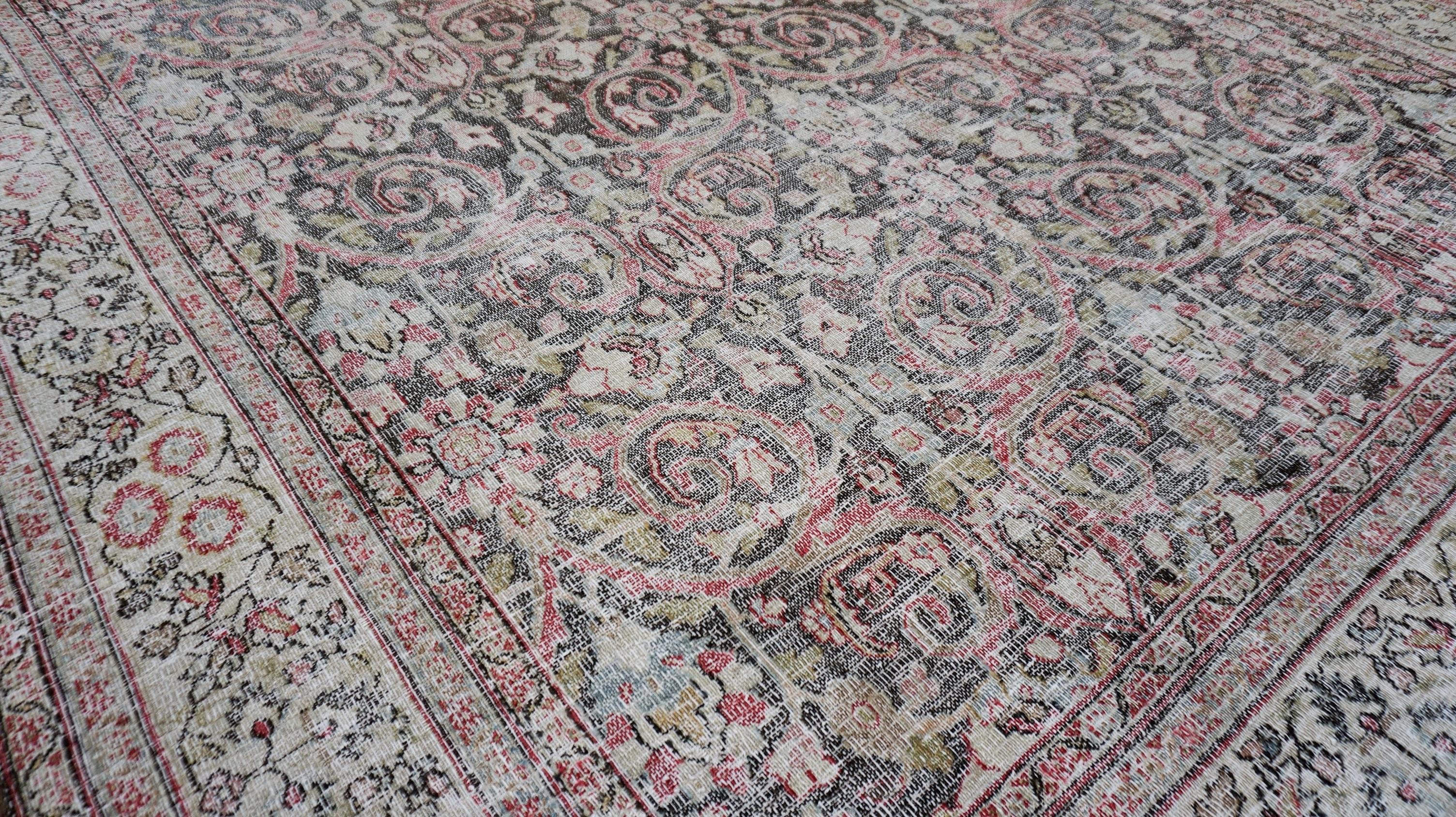 This antique hand-knotted wool rug showcases an exquisite blend of floral and scrollwork motifs, enriched by a timeworn patina that enhances its vintage charm. The intricate pattern, woven with traditional craftsmanship, features an elegant gray,