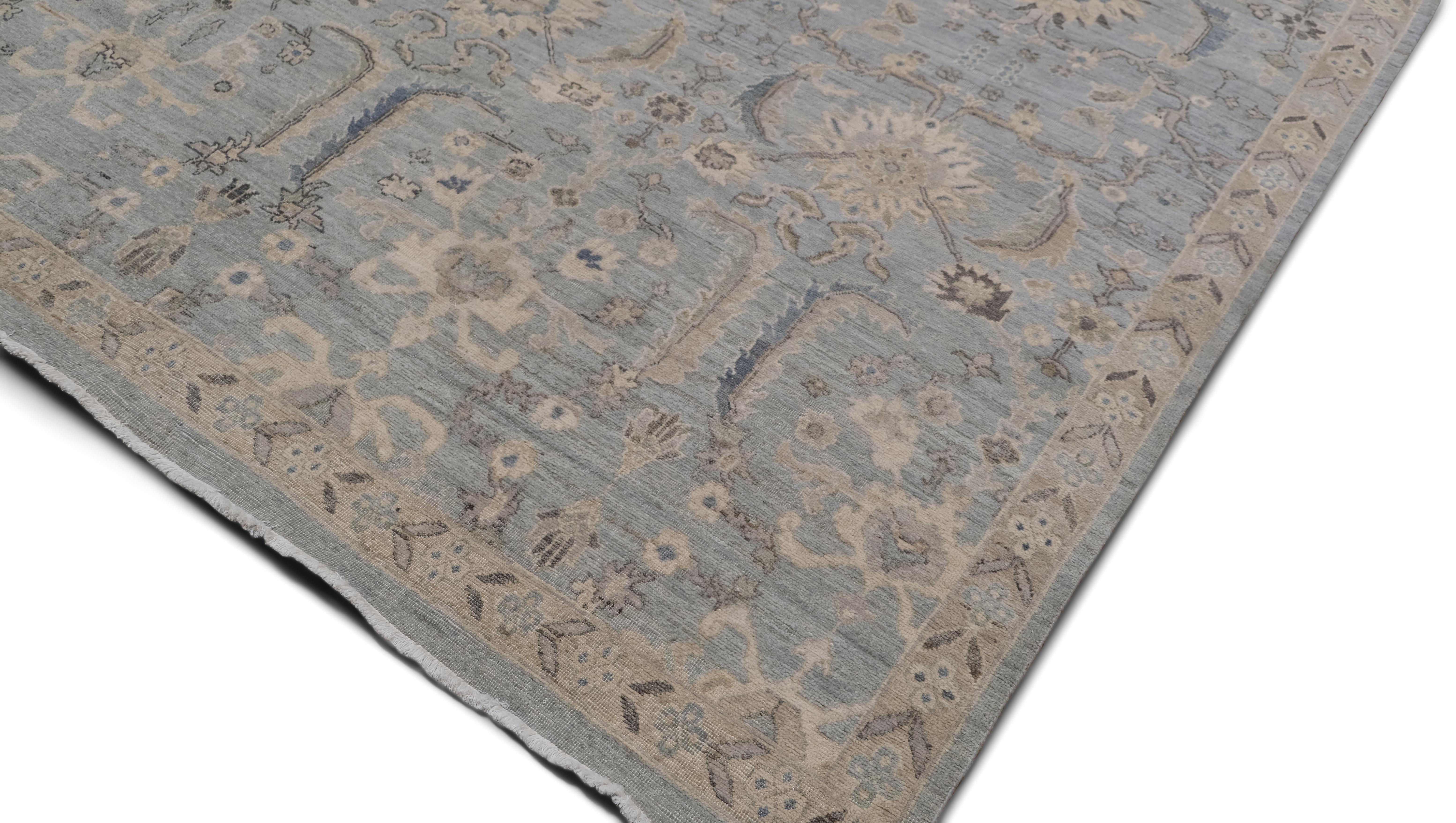 Questo raffinato tappeto in lana annodato a mano unisce un'estetica vintage a una raffinata lavorazione artigianale, con un intricato motivo a medaglioni floreali su un morbido sfondo blu e beige. Ispirato ai classici motivi persiani e Oushak, il