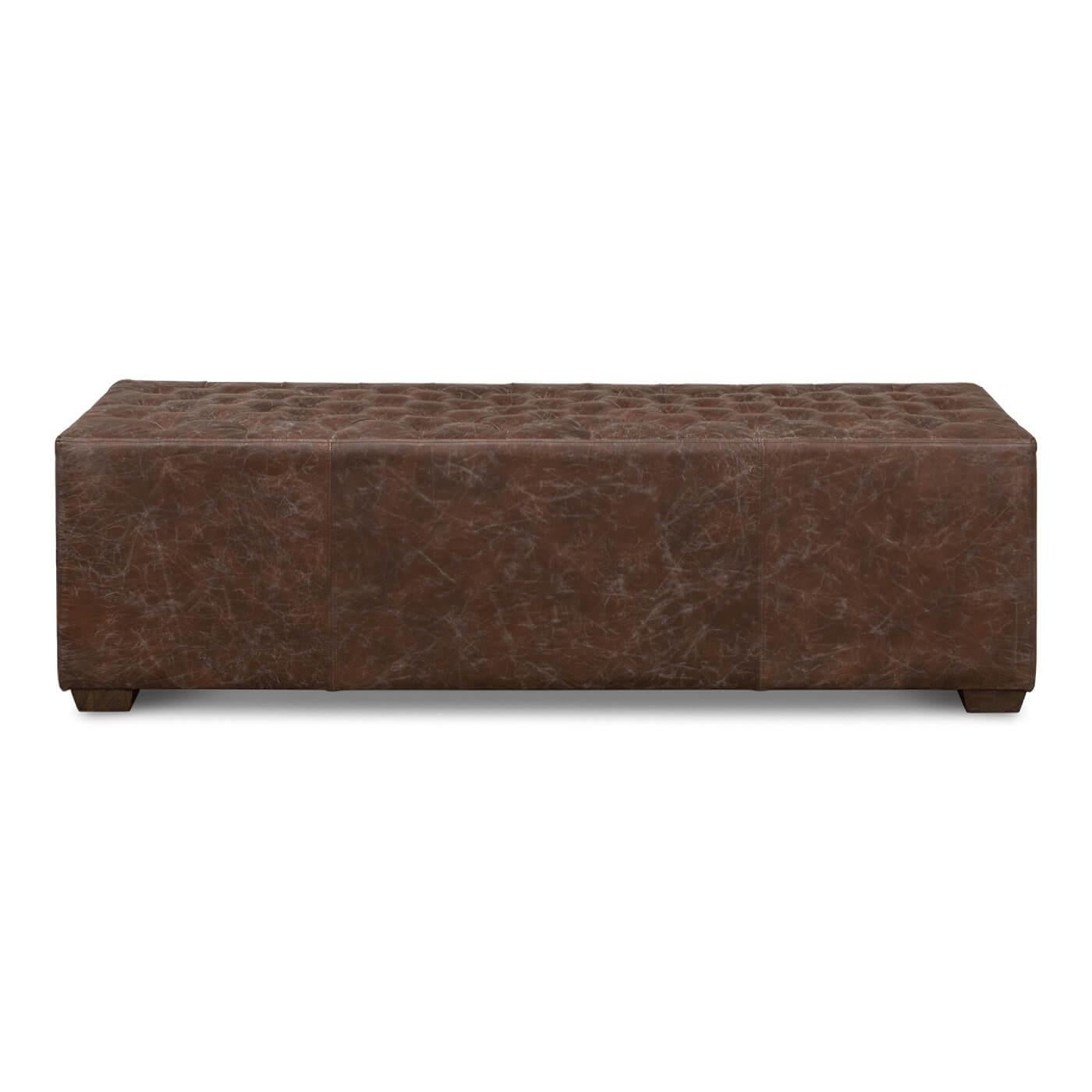 A distressed brown leather bench with a button-tufted top. It rests on oak block legs and has metal handles on the sides. 

Dimensions
59 in. W x 18 in. D x 17 in. H.


