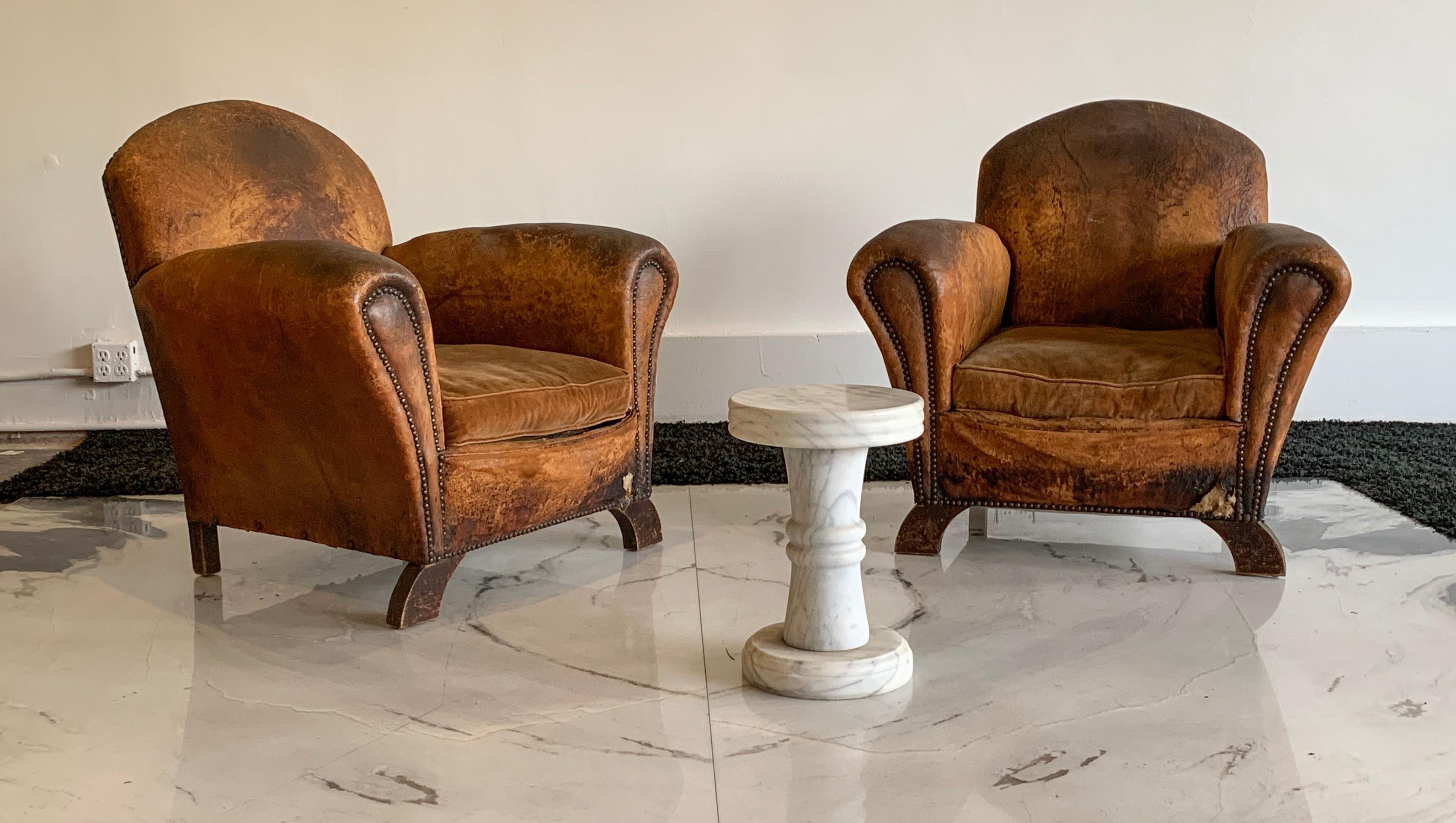 An absolutely fabulous pair of French Art Deco leather club chairs. These distressed leather club chairs are functional works of art and have age, wear and a patina that can only come from years worth of appreciation and only add to the beauty of