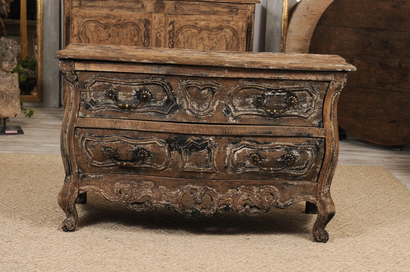 A French Louis XV style two-drawer 'commode en tombeau' from the late 19th century, with distressed finish, carved skirt and scrolled feet. This one was really a coup de foudre for us: we fell hard for the unusual, distressed finish, the intricate
