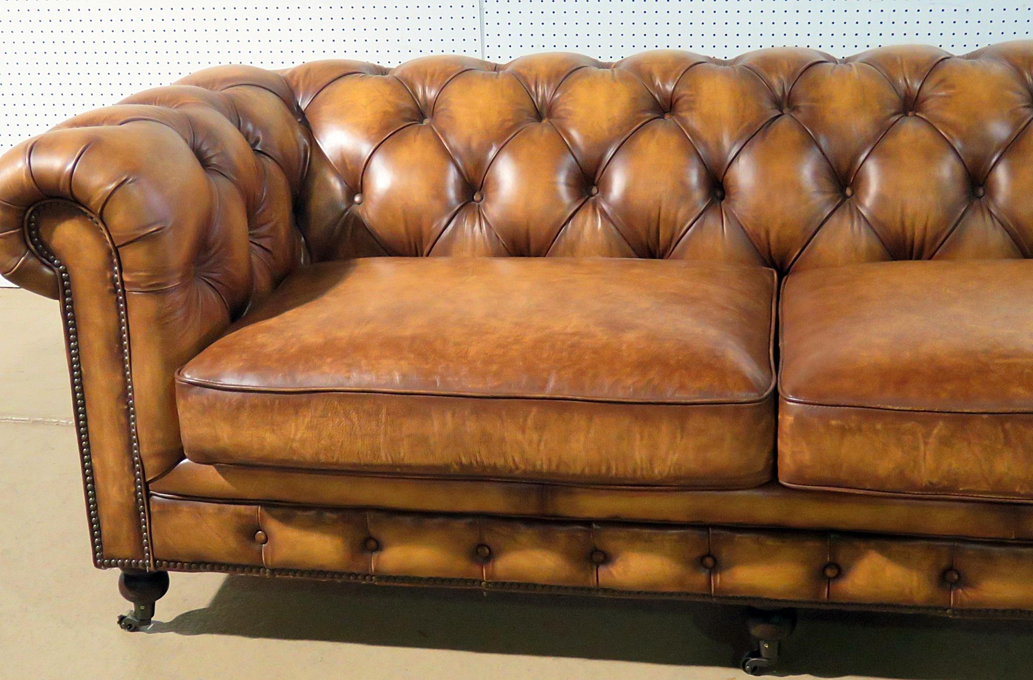 Distressed leather Chesterfield sofa with nailhead trim on casters.