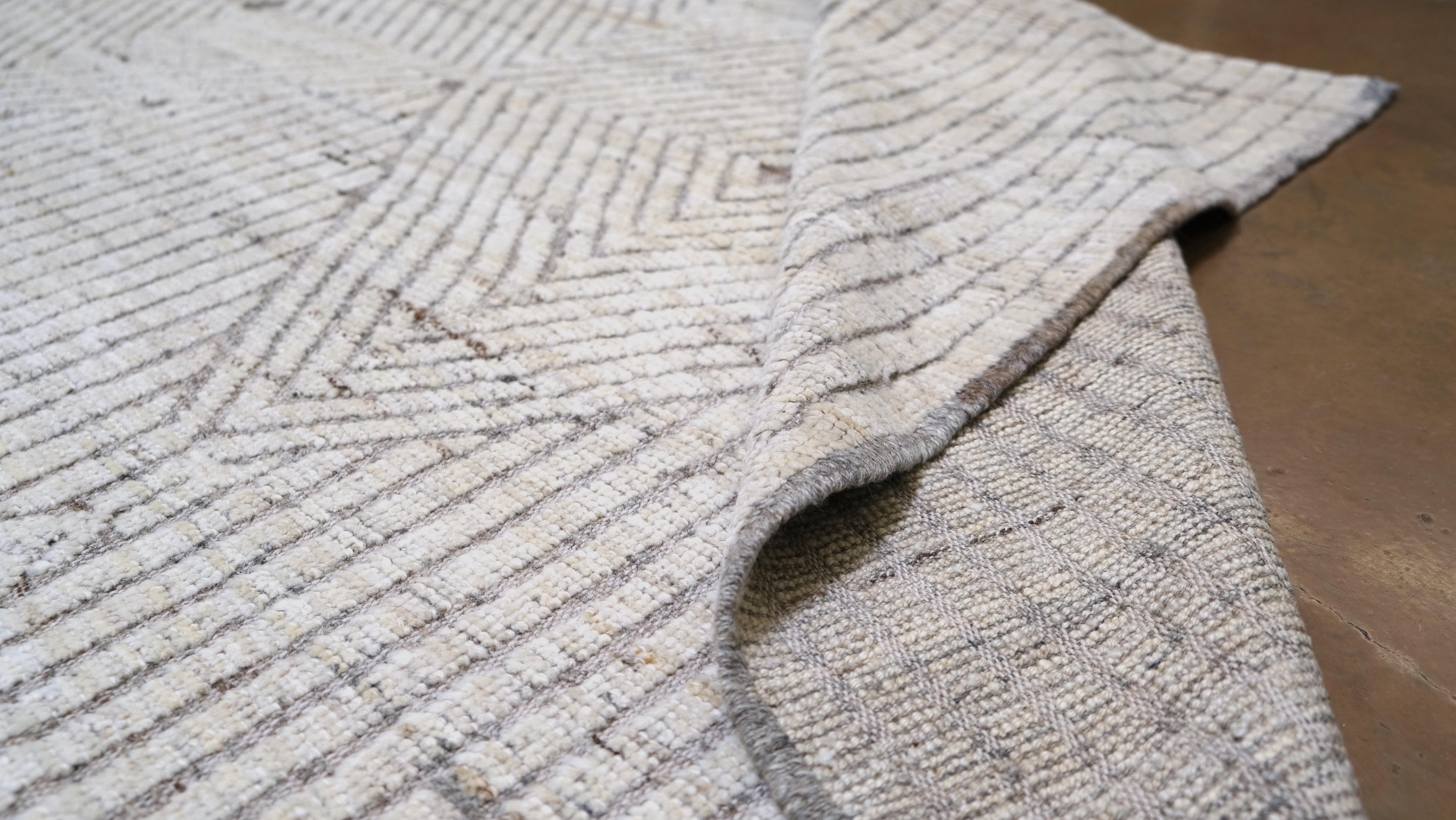Ein raffiniertes geometrisches Rautenmuster in dezenten Elfenbein-, Beige- und Hellgrau-Nuancen. Dieser Teppich verbindet nahtlos traditionelle Handwerkskunst mit einer modernen Ästhetik und ist damit die ideale Wahl für zeitgenössische,