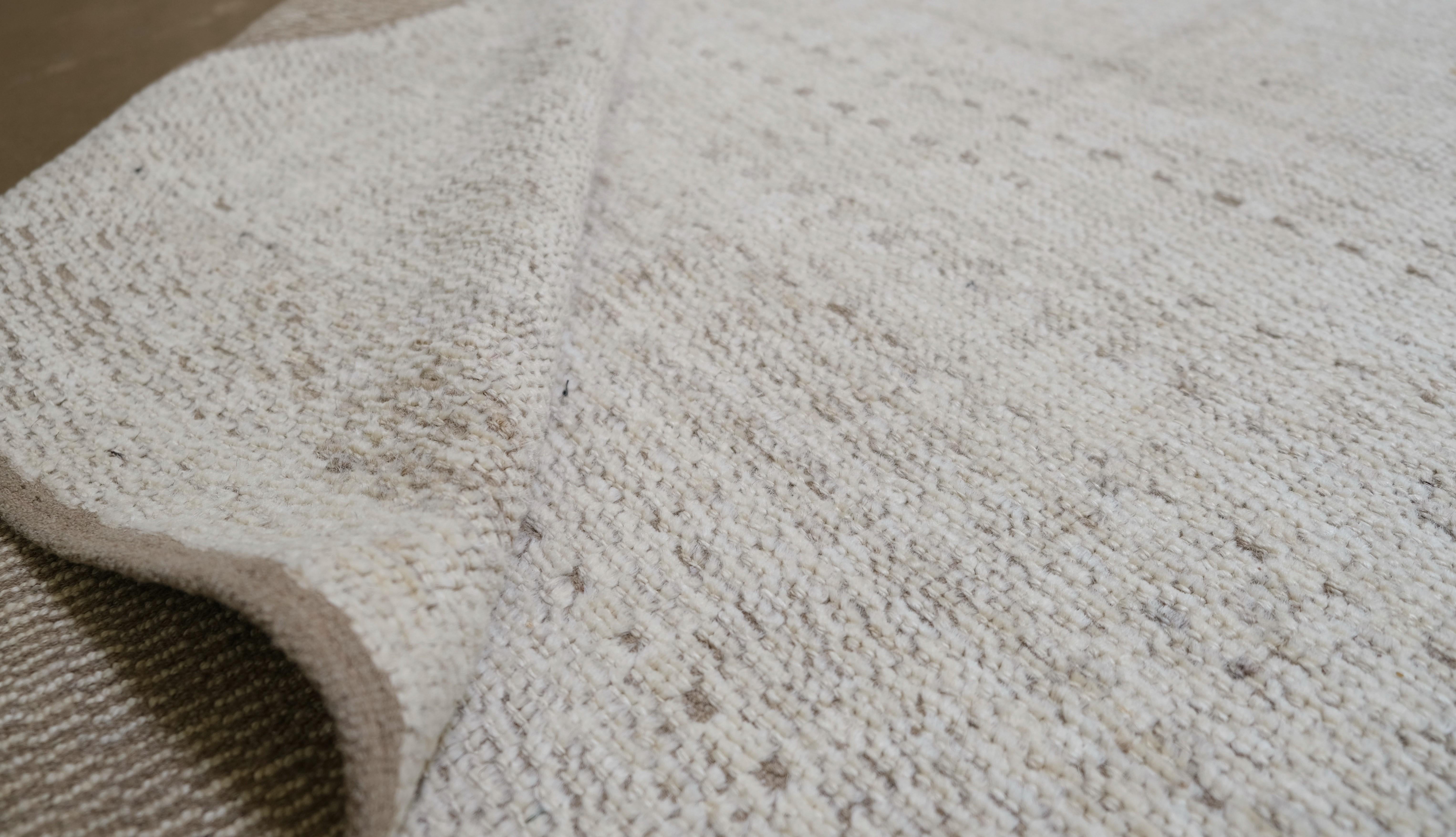 Elevate your interior with this exquisite hand-knotted wool rug, featuring a contemporary wave-inspired pattern in soothing neutral tones. This luxurious piece offers a perfect blend of modern design and traditional craftsmanship, making it a
