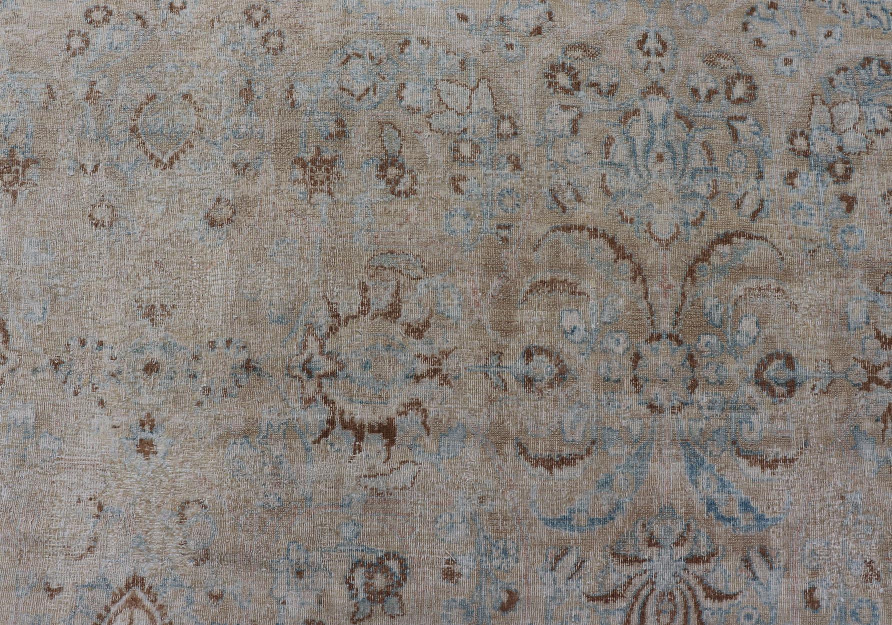 Antique Persian Mashhad distressed carpet with tan and blue floral and medallion design, / ZIR-51-KV-10. Persian Mashhad floral design. 

Measures:10'2 x 12'9 

This muted antique distressed Persian Mashhad carpet is primarily characterized by