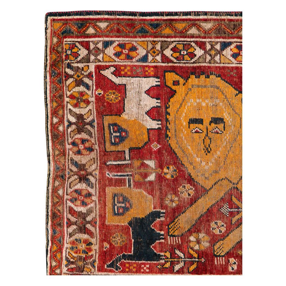 An antique Persian Gabbeh tribal rug handmade by the nomadic Qashqai tribe in South Persian during the early 20th century. One large orange folksy lion prances over the deep red field and is surrounded by 4 smaller black and white lions. This