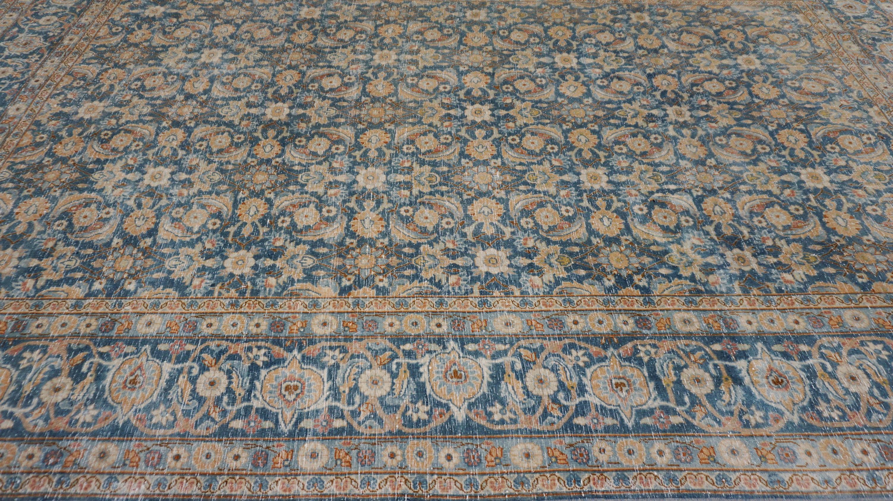 Ce magnifique tapis en laine noué à la main présente un médaillon floral intemporel dans une magnifique palette de bleus délavés. S'inspirant des motifs traditionnels persans Tabriz et Herati, le motif all-over complexe comprend des vignes