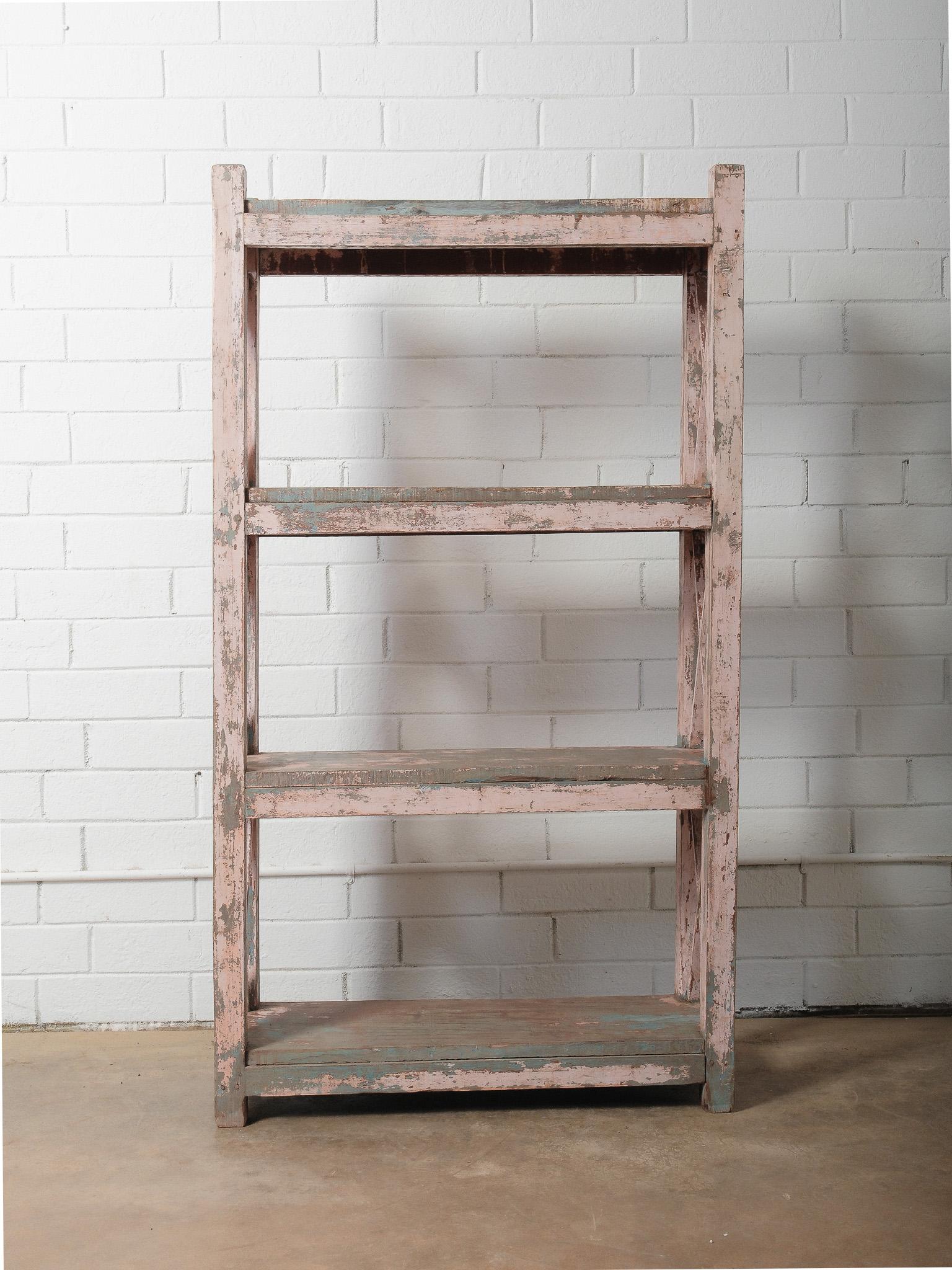 Un'antica mensola in legno splendidamente usurata che mostra strati di vernice rosa e verde acqua, rivelando decenni di età autentica e patina naturale. La finitura anticata mette in risalto i toni tenui del blush, i tenui sottotoni verdi e le