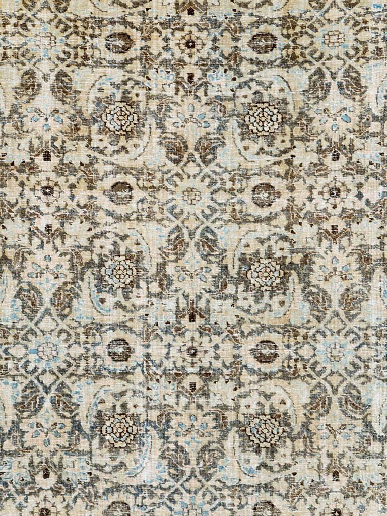 A vintage Persian Tabriz room size carpet with a distressed appeal from the mid-20th century. The all-over Herati pattern is dressed in nude and slate blue over a charcoal brown field. The reversing turtle design in the border is in charcoal brown