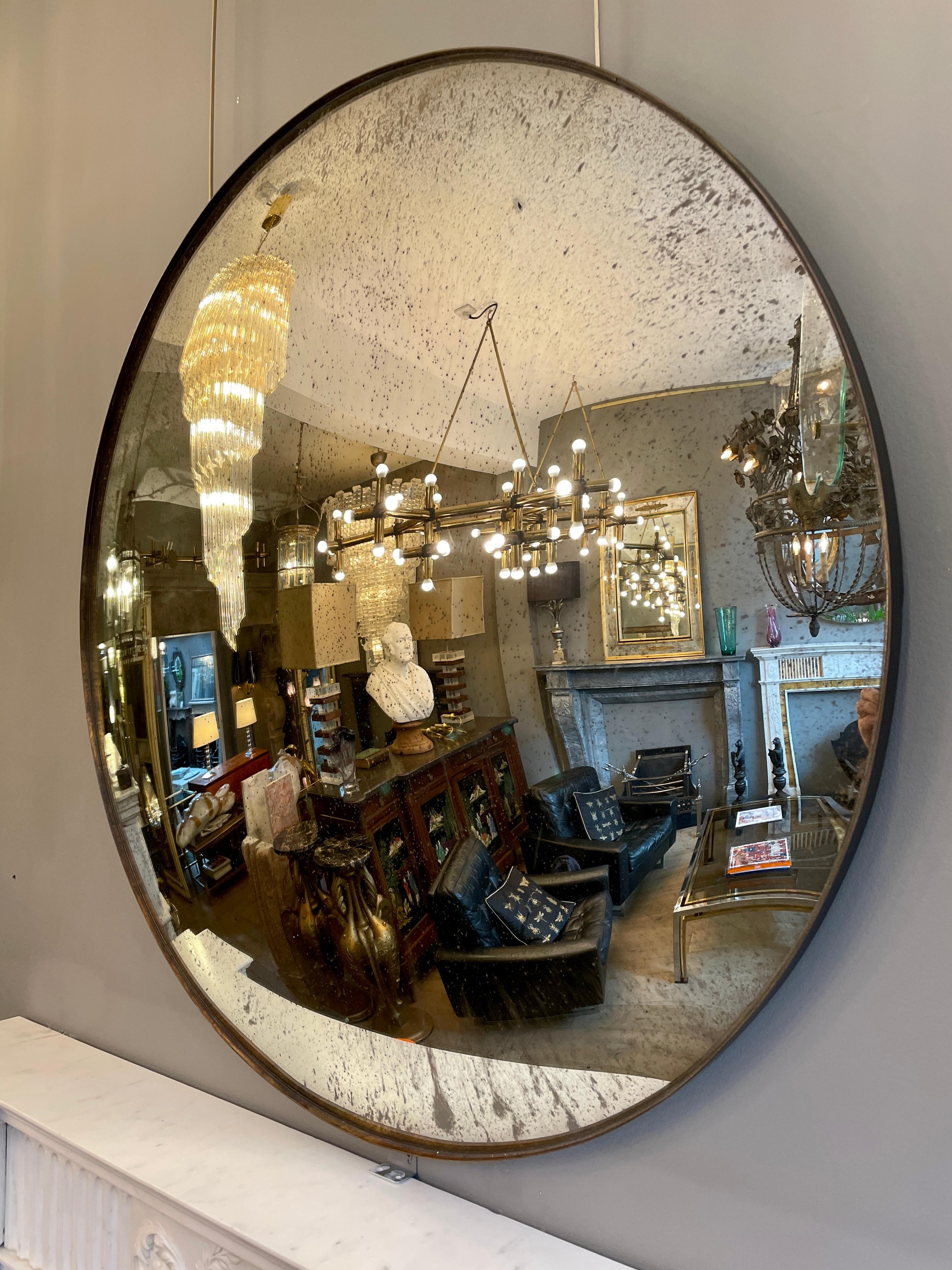 A large circular distressed silvered convex mirror with bronze finish frame. Contemporary.
