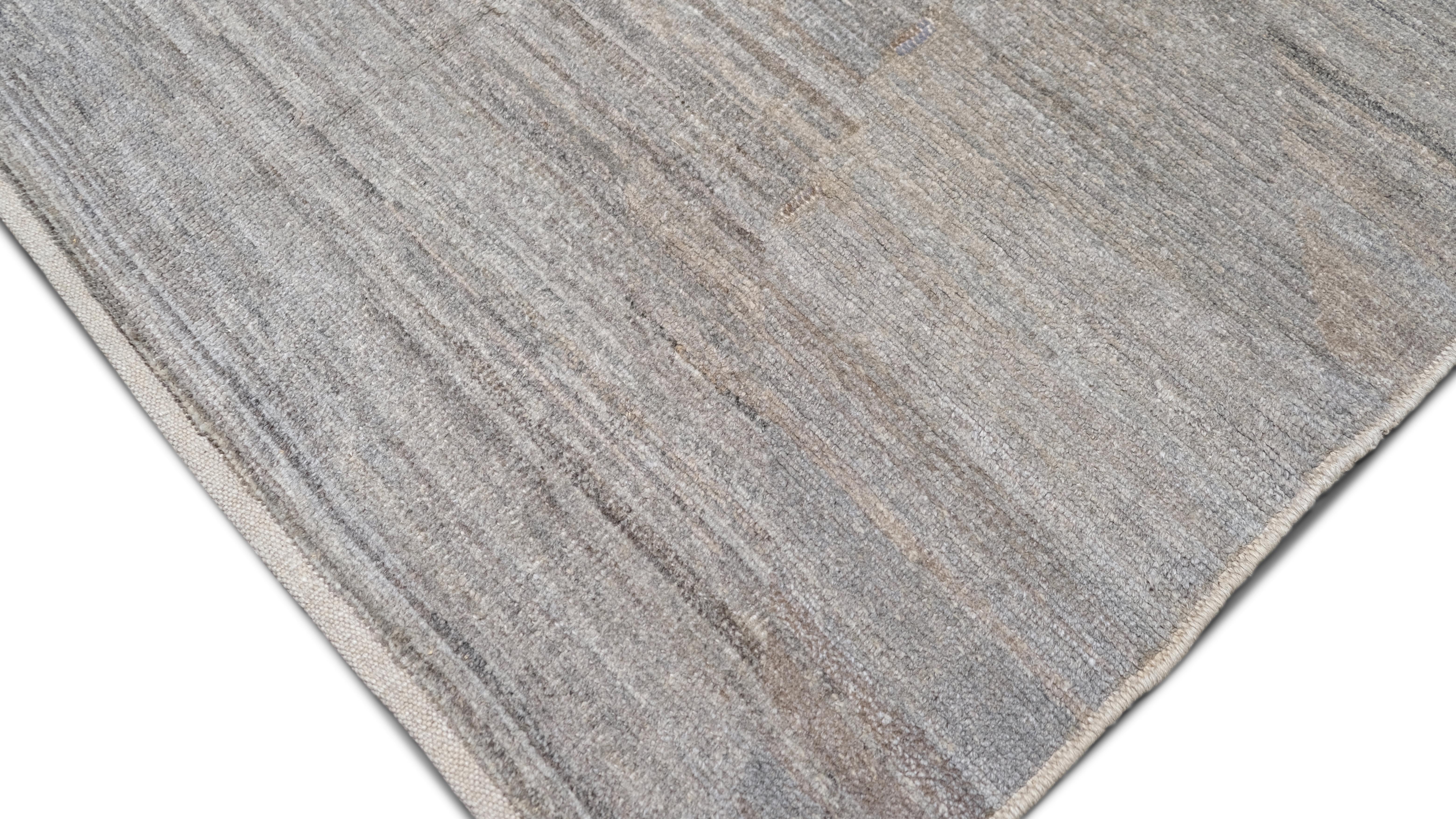 Dieser handgeknüpfte Wollteppich wertet Ihr Interieur durch seine schlichte Raffinesse auf. Dieses minimalistische Design mit seinem subtilen braun-grauen Muster eignet sich perfekt für moderne, zeitgenössische oder Übergangsräume. Die neutralen