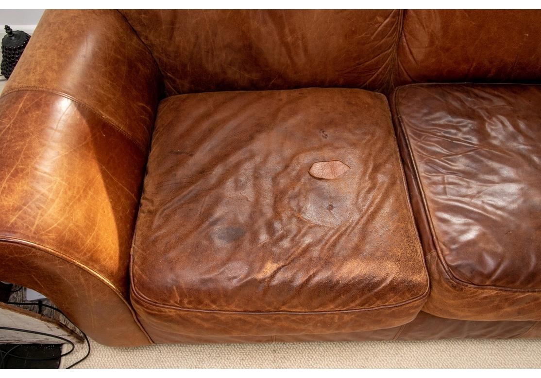Very comfortable vintage leather sofa with Bomber Jacket type leather in a worn and faded condition. Very comfortable and still having good support. Flat panel arms, front wood block foot and detached seat and back pillows. There is a leather