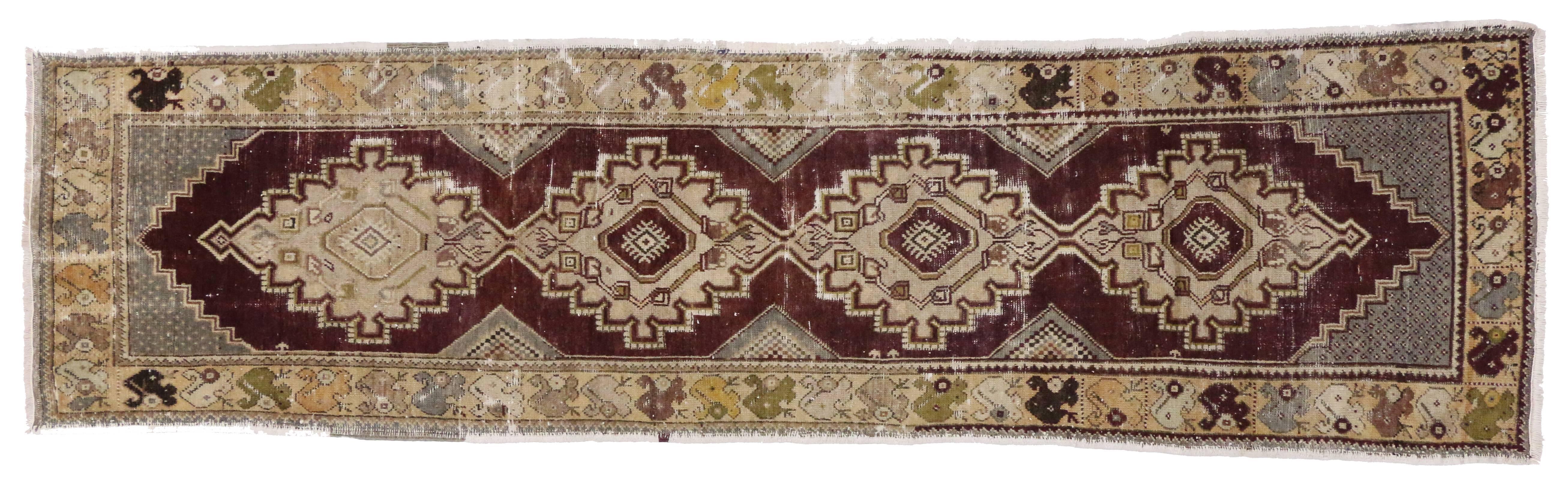 51228 a vintage Oushak rug runner. This classic Oushak runner is patterned in a geometric Primitive style. The Oushak runner features four connected beige medallions centred with a symbol of the 'evil eye' for protection. Slate gray spandrels and