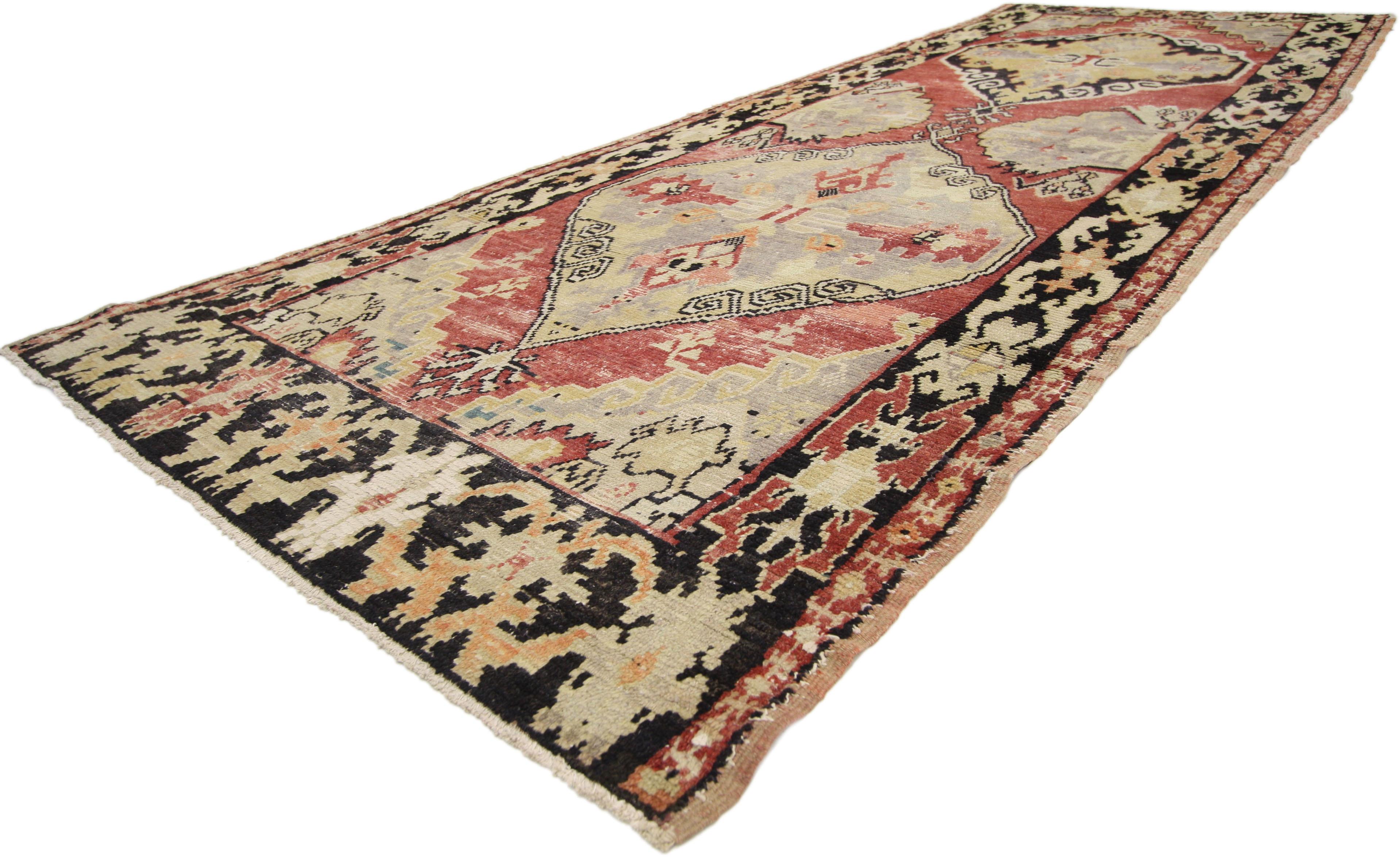 50277, distressed vintage Turkish Oushak runner with rustic lodge style, hallway runner. This hand knotted wool vintage Turkish Oushak runner features two large stepped hexagonal medallions anchored with Anatolian pendants spread across an abrashed