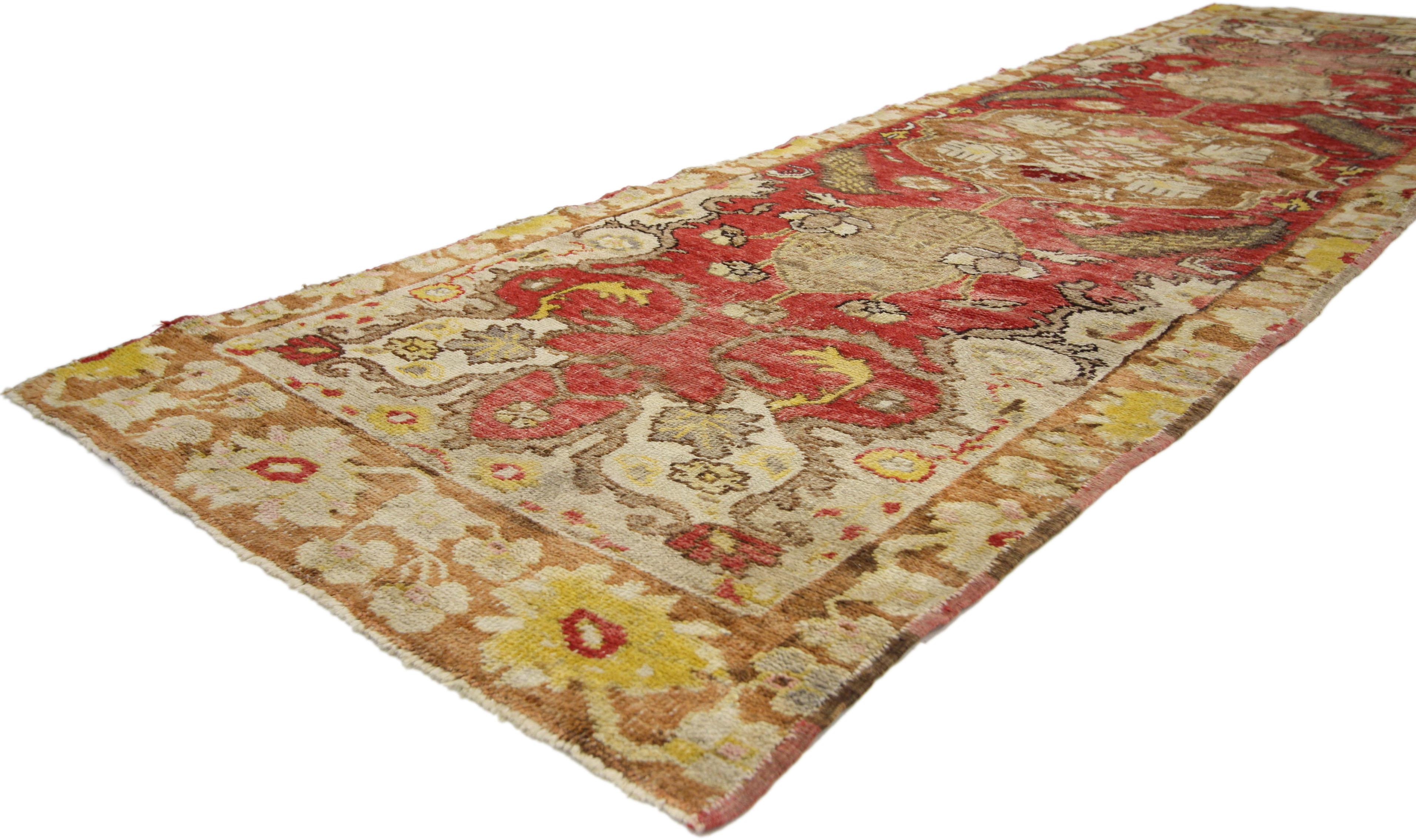 51189, distressed vintage Turkish Oushak runner with rustic neoclassical style. This hand knotted wool vintage Turkish Oushak runner features a round medallion anchored with pinecone shaped pendants spread across an abrashed red field. The central