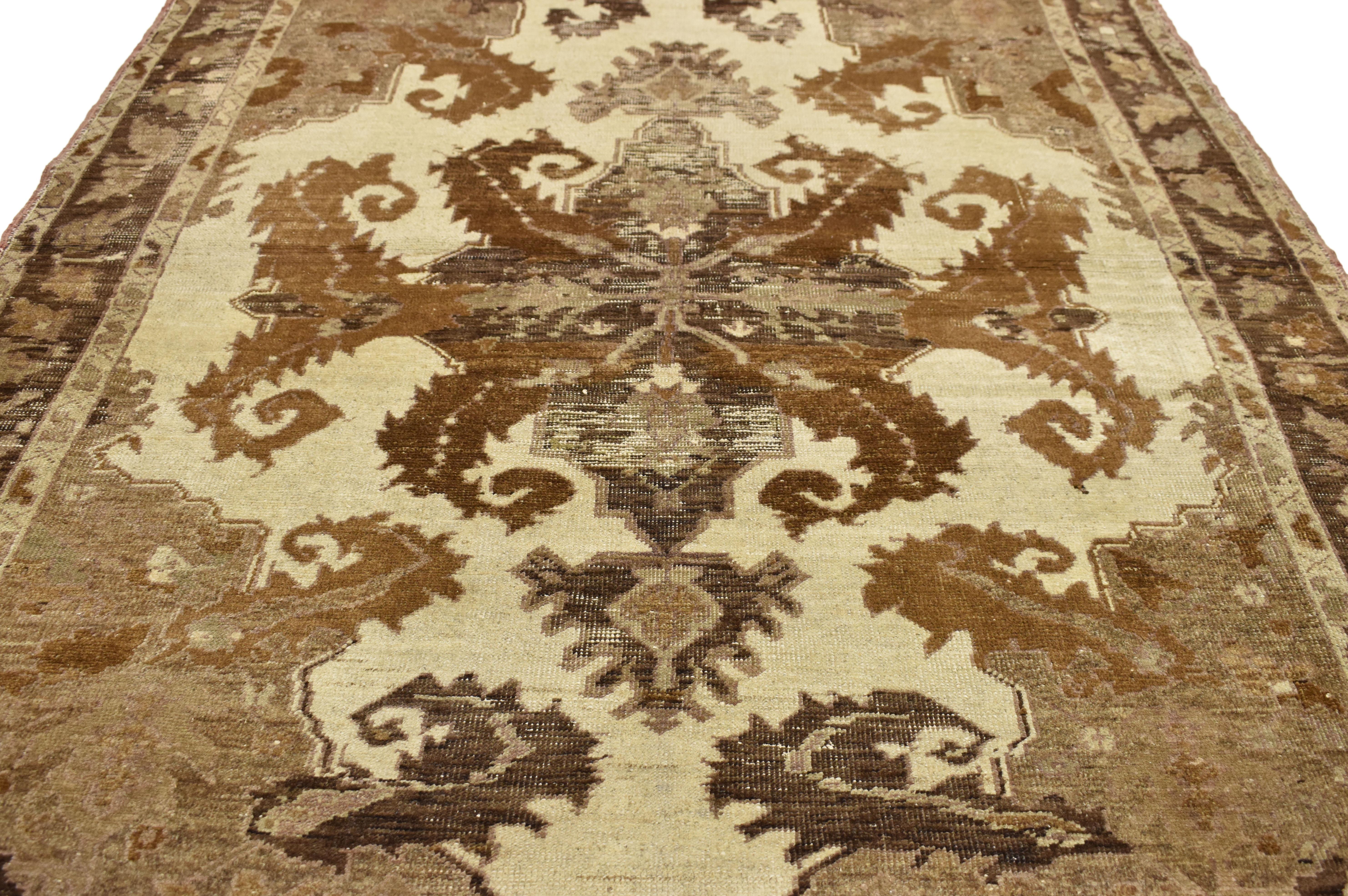 73661, distressed vintage Turkish Oushak with Black Forest style. This hand knotted wool distressed vintage Oushak rug features large scale foliate patterns in warm, neutral earth-tones. Sickle leaf forms curl both out from a center medallion and