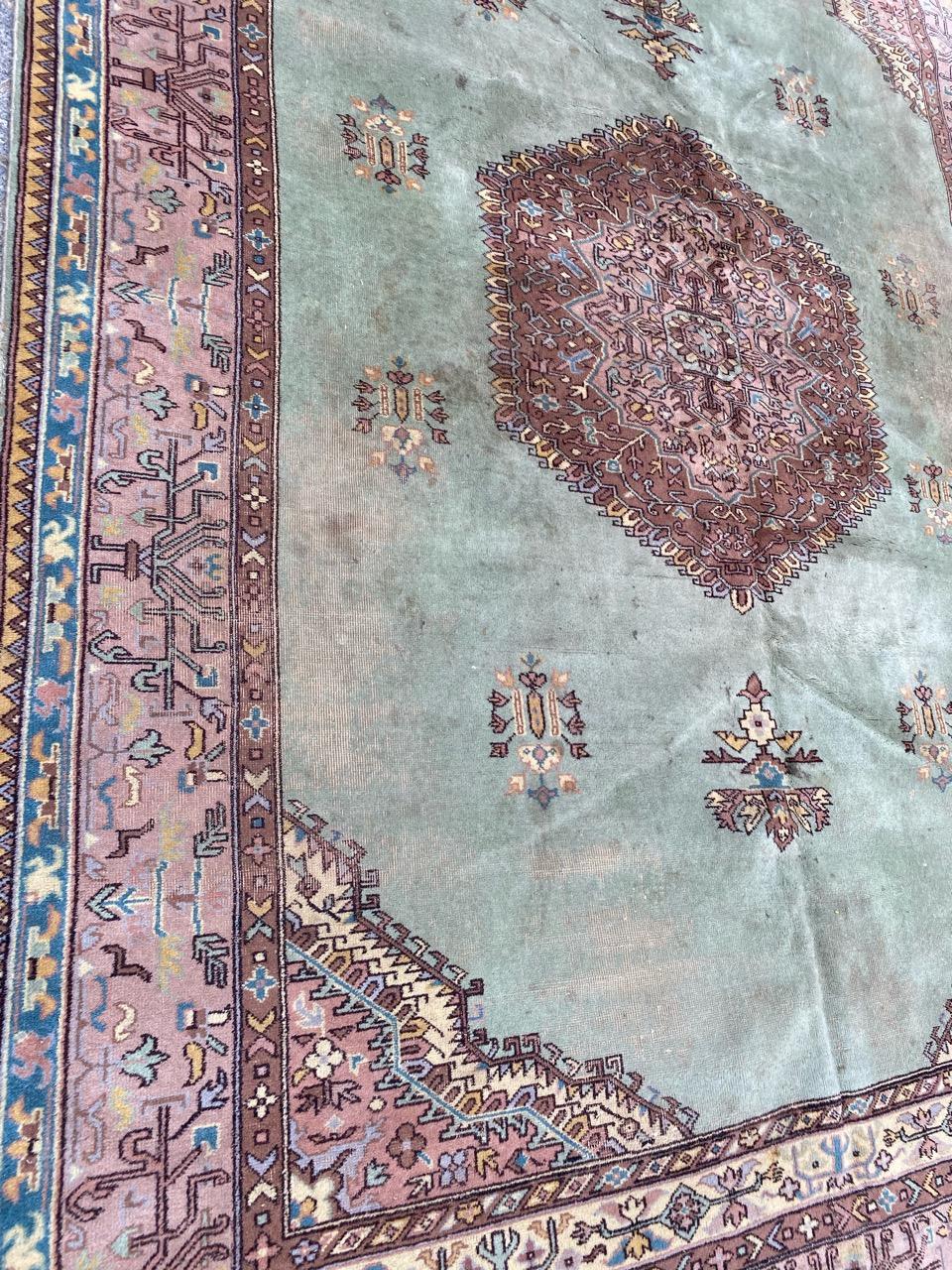 Mid century distressed Turkish rug with a floral and central medallion design and beautiful green field colors, entirely hand knotted with wool velvet on wool foundation.