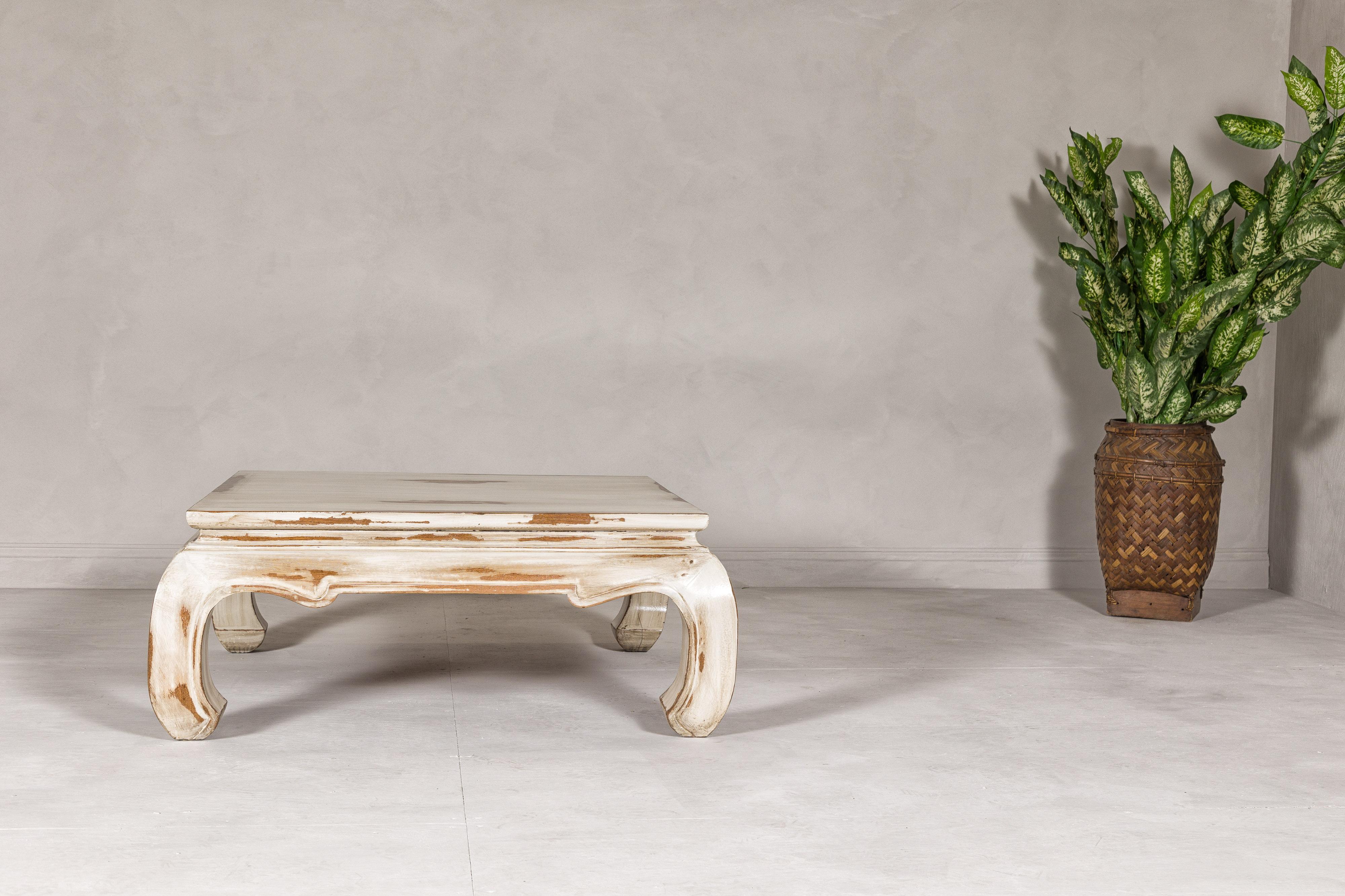 A vintage distressed white color coffee table from the 20th century with chow legs and square top. Experience a blend of history and elegance with this vintage coffee table from the 20th century, a delightful addition to any home seeking a touch of