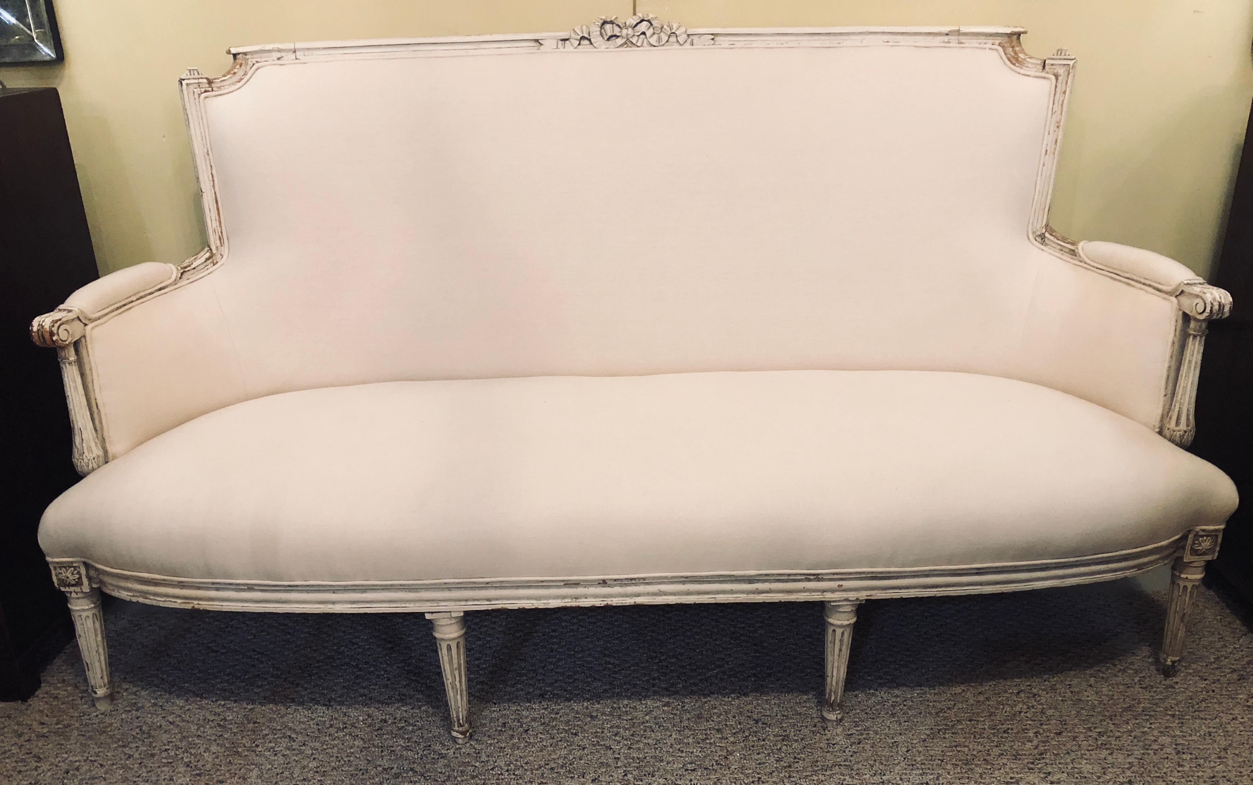 A late 19th or early 20th century distressed white paint decorated Louis XVI style Swedish canopy or small sofa. This finely original paint decorated sofa is slightly longer than a settee yet not really large enough to be a full sofa. The original