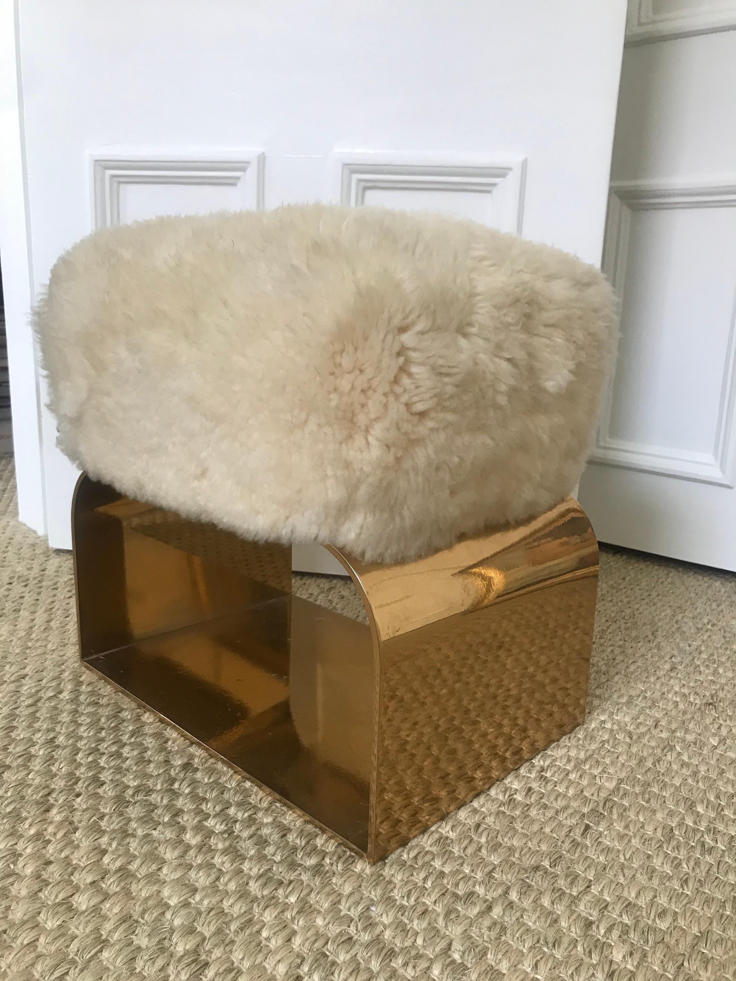 Polished brass base with a natural Patagonian sheepskin top.

NOTE: A tuft of sheepskin is detached as seen in top right corner of last photograph. It could possibly be repaired but may require the whole seat to be reupholstered.