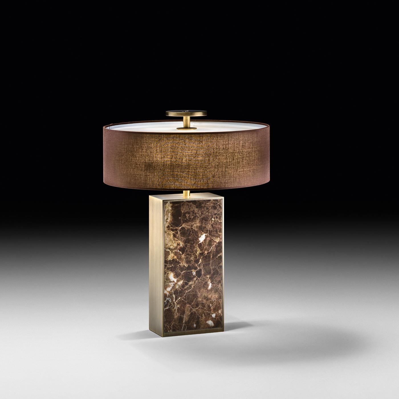 Infused with sophistication and charm, this stunning lamp is a modern and opulent piece of functional decor. It features a drum-shaped lampshade made of a brown rigid fabric, and supported by a rectangular base of Emperador marble. This superb lamp