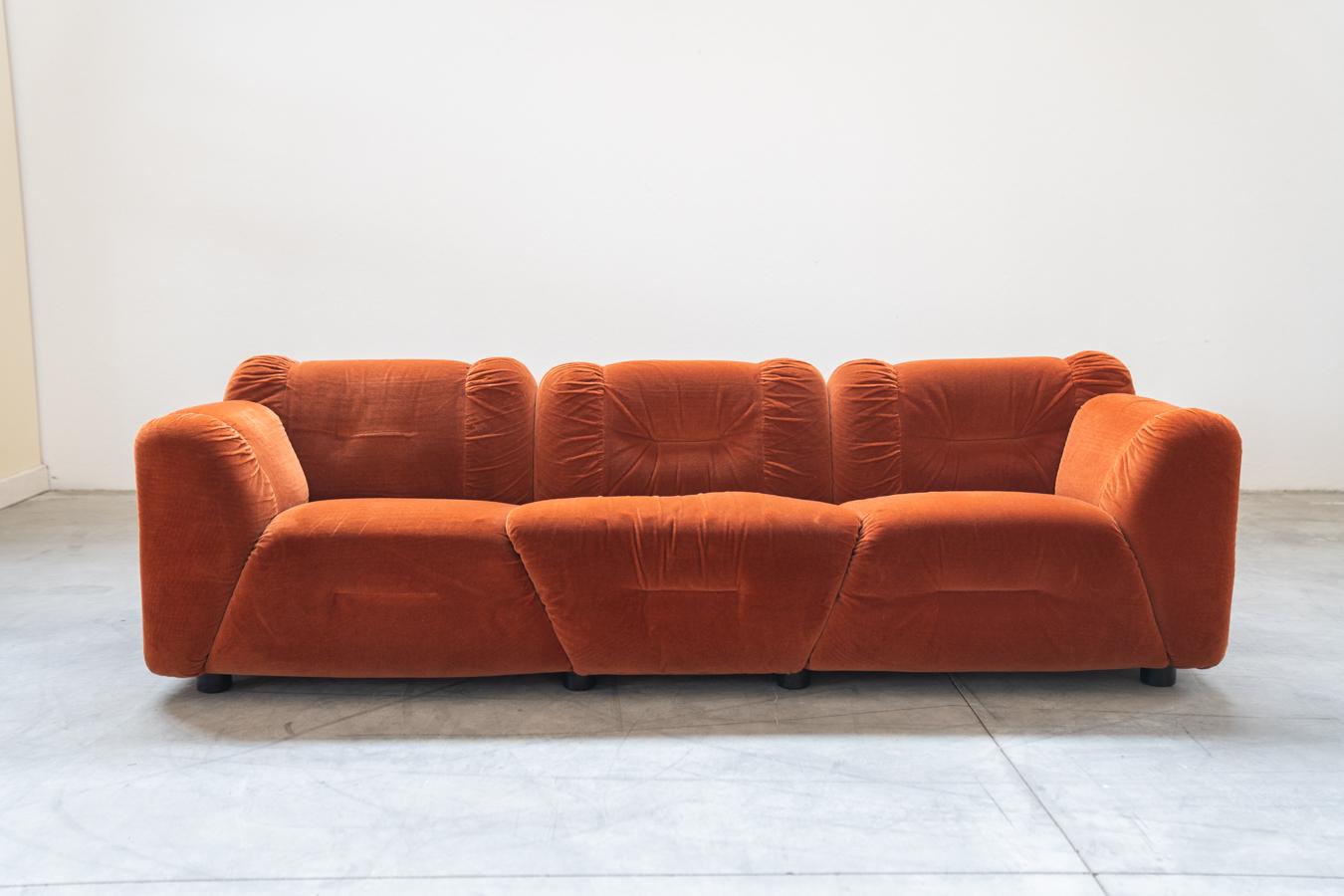 Orangefarbene Chenille-Sofas, zwei- und dreisitzig, 2er-Set, 1970er Jahre
Rahmen aus Holz, Füße aus Kunststoff. Die Rückenlehnen der beiden Sofas  	weist leichte zeitbedingte Gebrauchsspuren auf.
MASSNAHMEN	3-Sitzer Sofa: H65 x B230 x T90 - Sitzhöhe