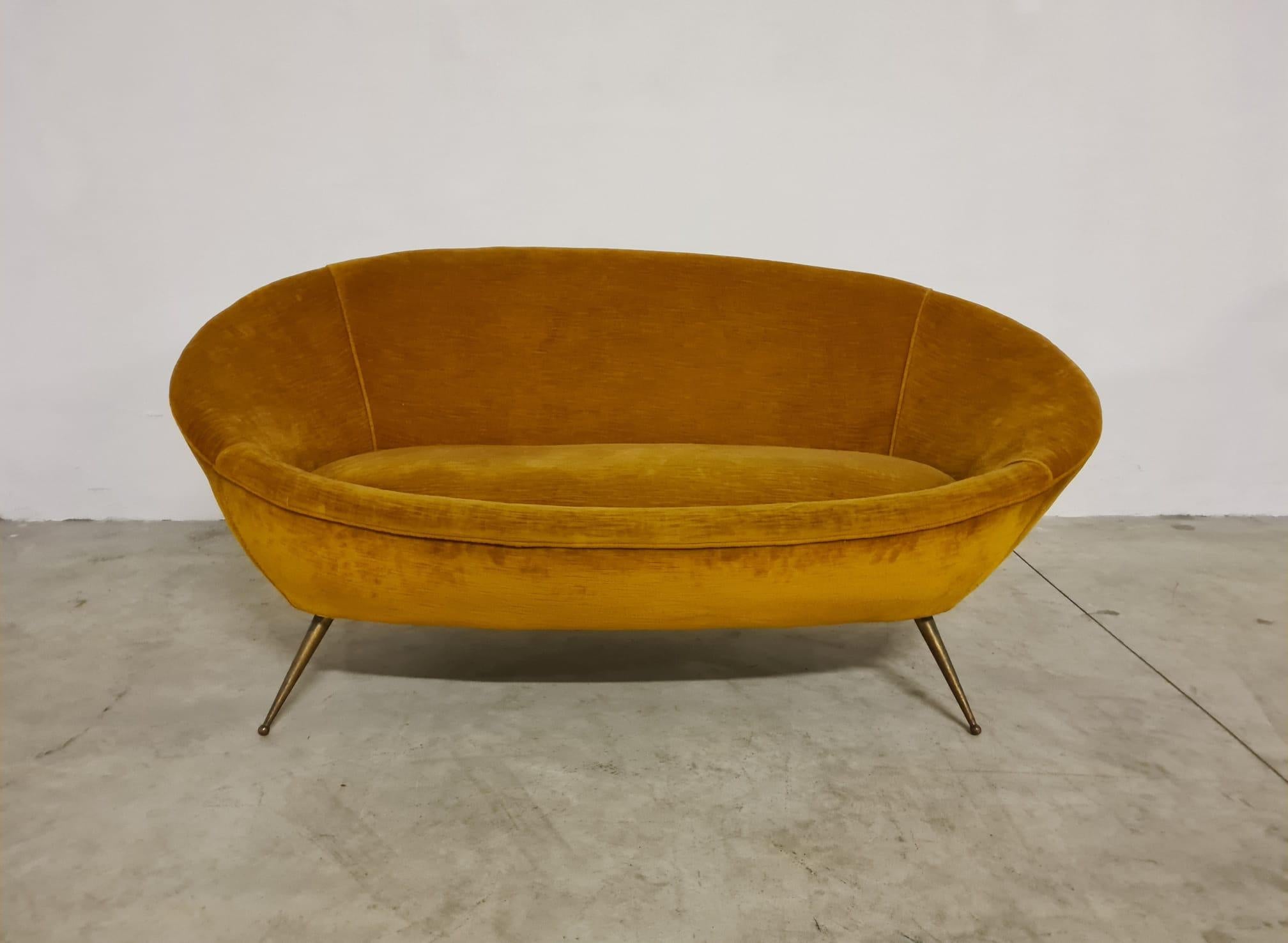 Sofá de los años 60 de fabricación italiana.

Elegante sofá de dos plazas con forma de huevo y patas cónicas de latón.

Forro de terciopelo ocre original de época.

Pequeña y refinada, es ideal para espacios reducidos.

El sofá se encuentra en